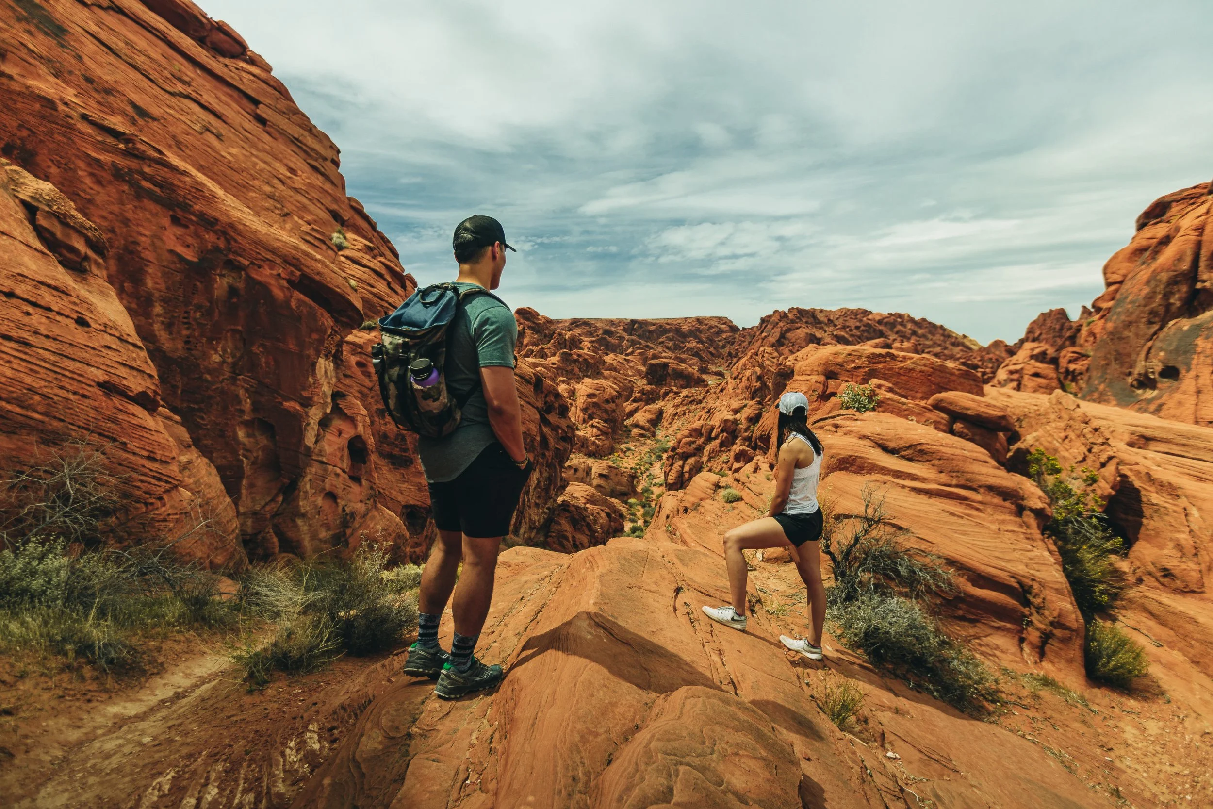 Hikers looking out at red sandstone rock formations at Valley of Fire State Park Nevada, desert adventure photography by James Brasier