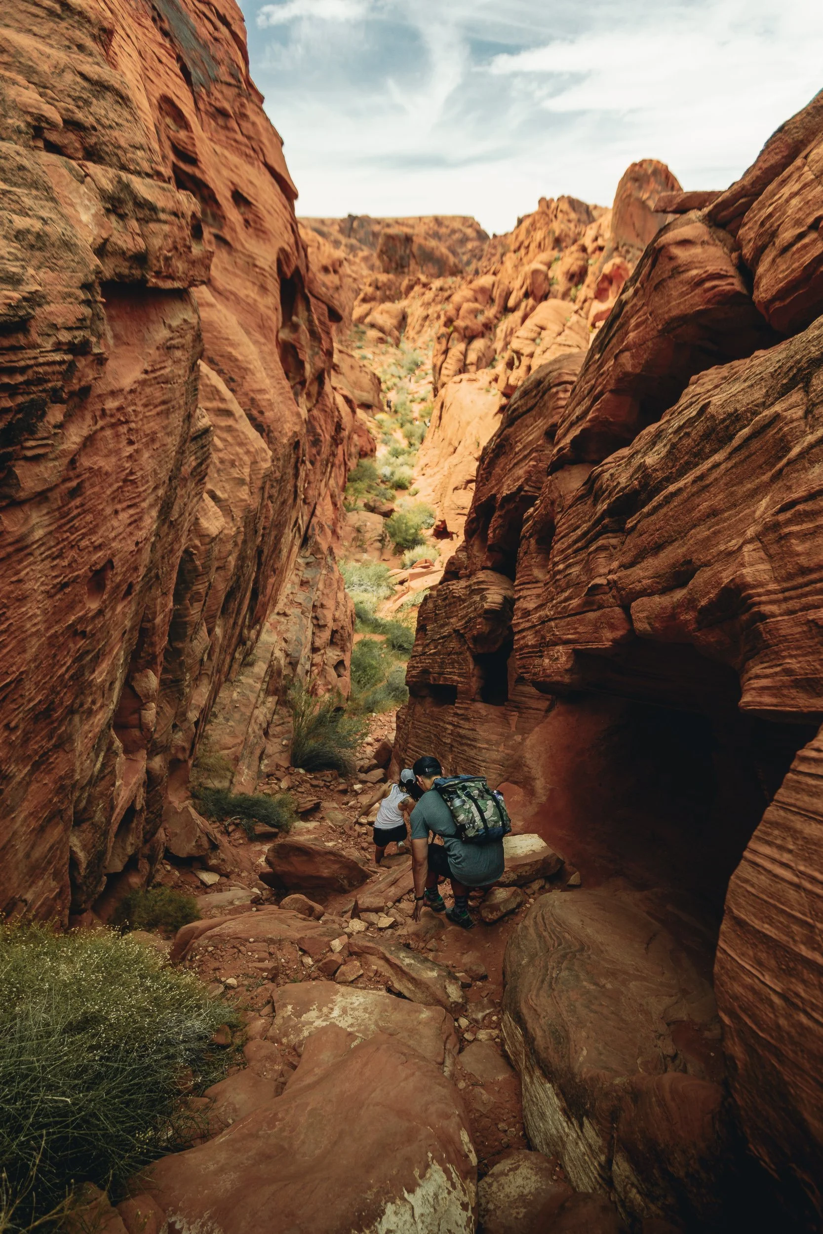 Hikders exploring a narrow red sandstone canyon at Valley of Fire State Park Nevada, outdoor landscape photography by James Brasier
