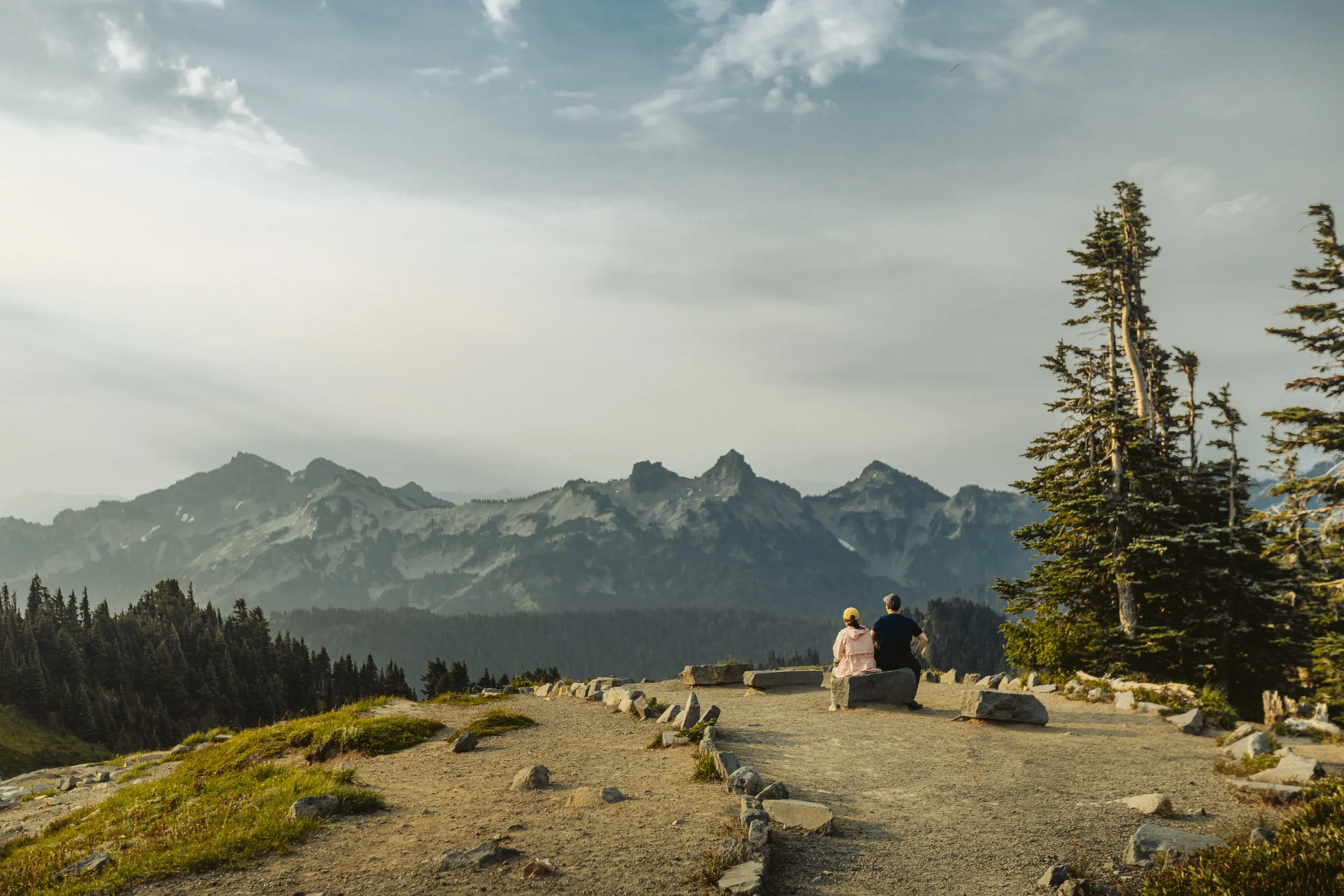 Two people sitting at a viewpoint overlooking the Cascade Range at Mount Rainier National Park, Washington landscape photography by James Brasier