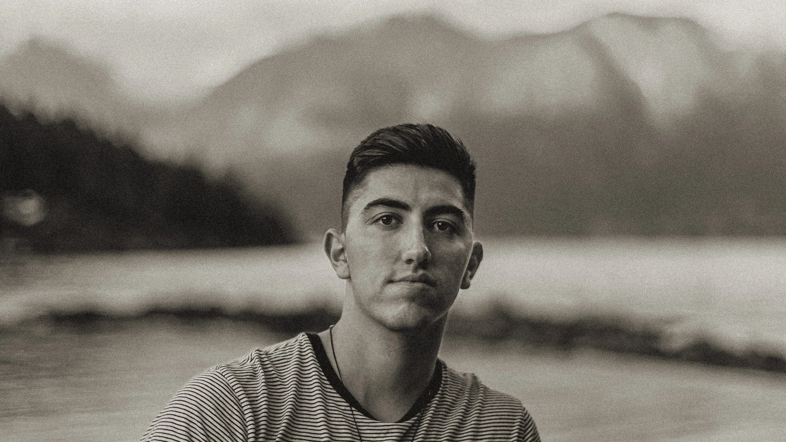 Black and white portrait of photographer James Brasier on Bowen Island, British Columbia, with ocean and mountains in the background