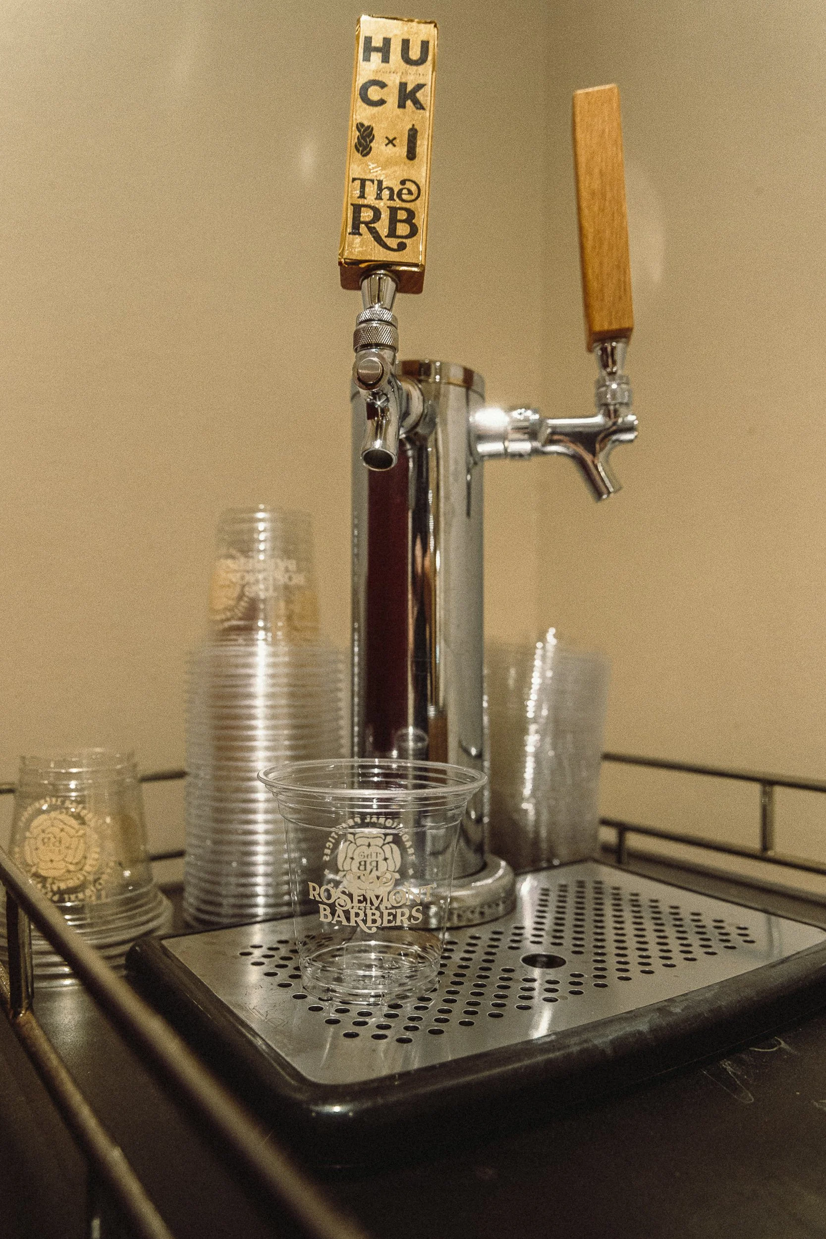 Custom-built cold-brew coffee tap with branded glassware at The Rosemont Barbers, commercial detail photography by James Brasier