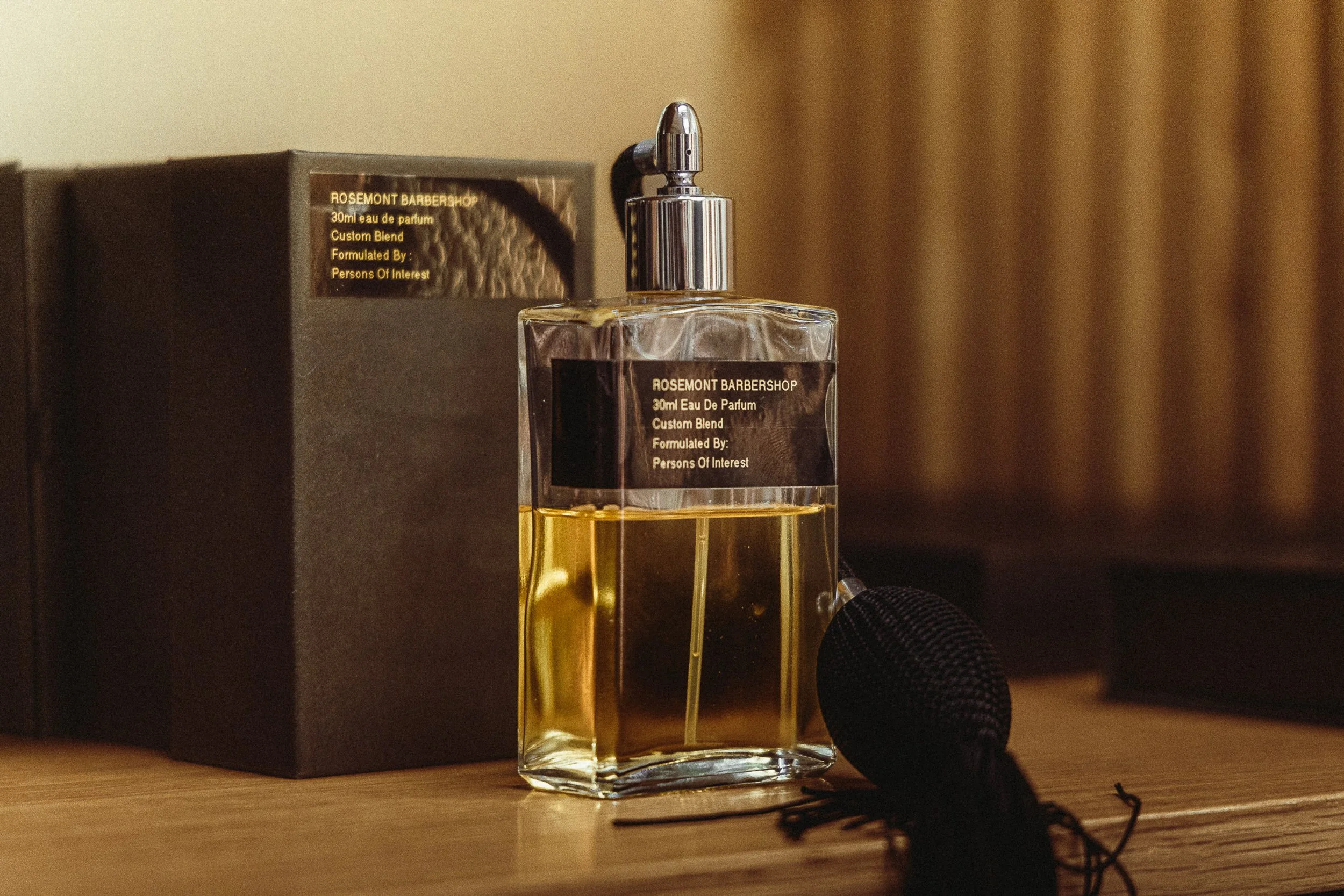 Custom Rosemont Barbershop eau de parfum bottle by Persons of Interest on a wooden shelf, product detail photography by James Brasier