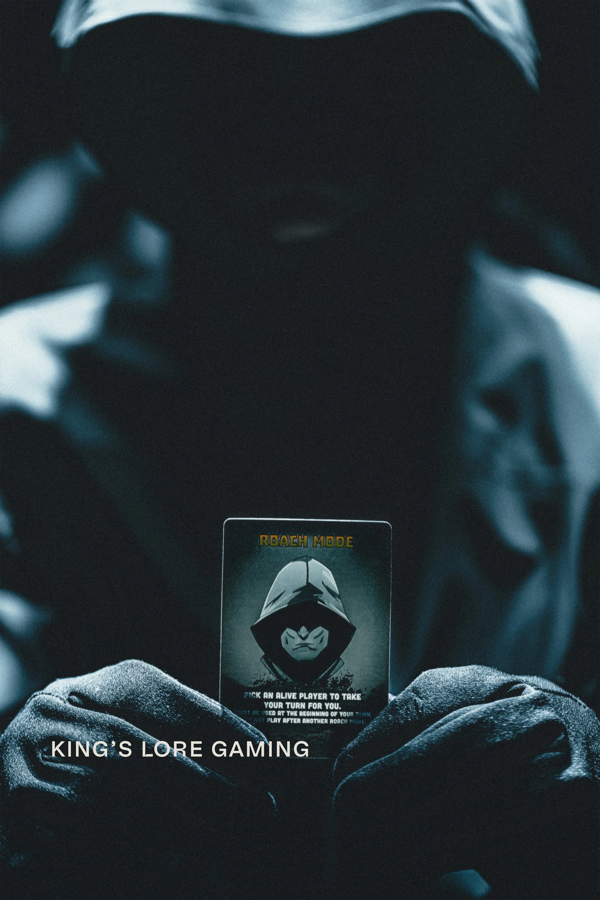 Hooded figure holding ZETA Survival Roach Mode card in dark cinematic blue tones, product campaign photography for Kings Lore Gaming by James Brasier