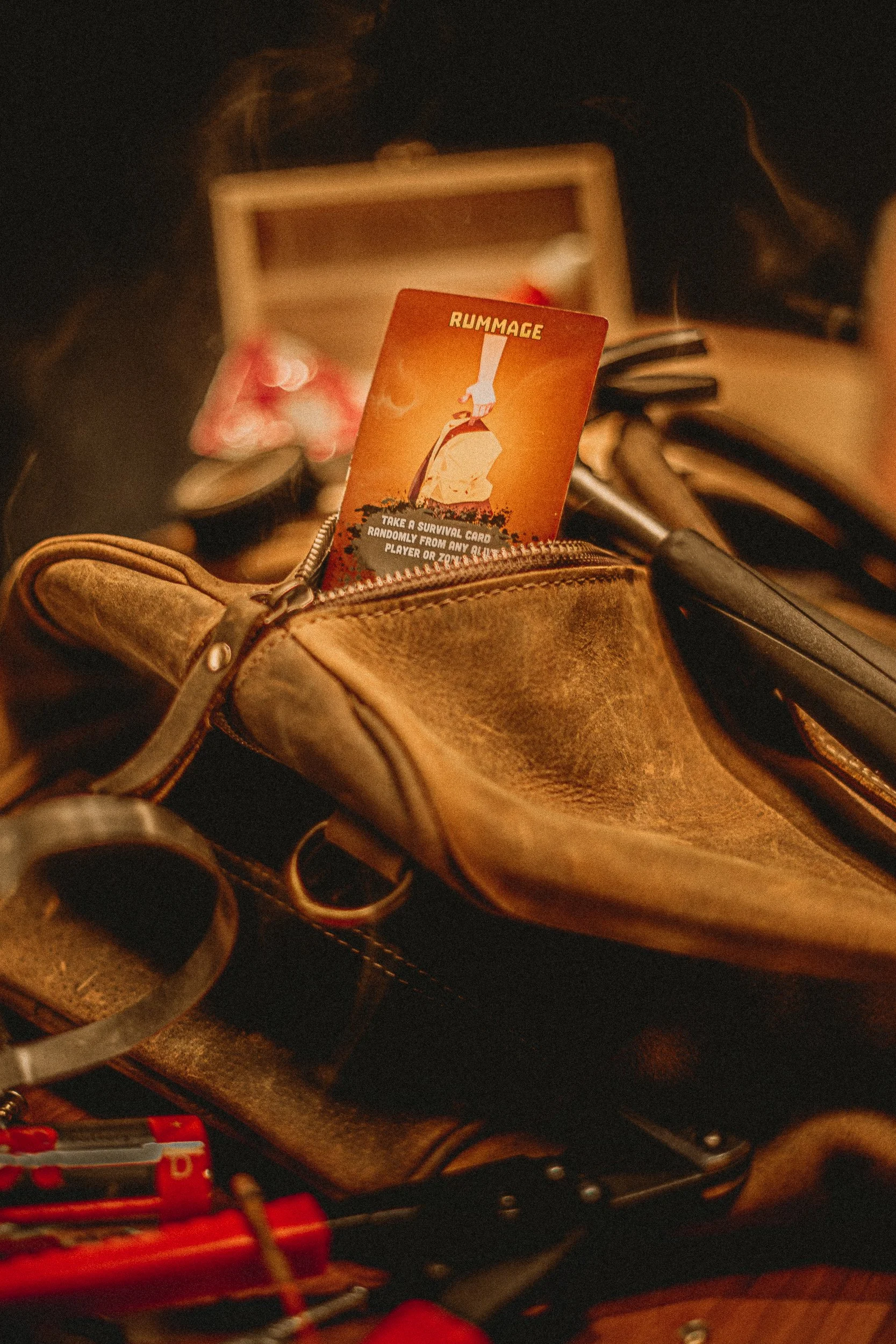 ZETA Survival Rummage card tucked into leather bag with tools and smoke, styled product photography by James Brasier