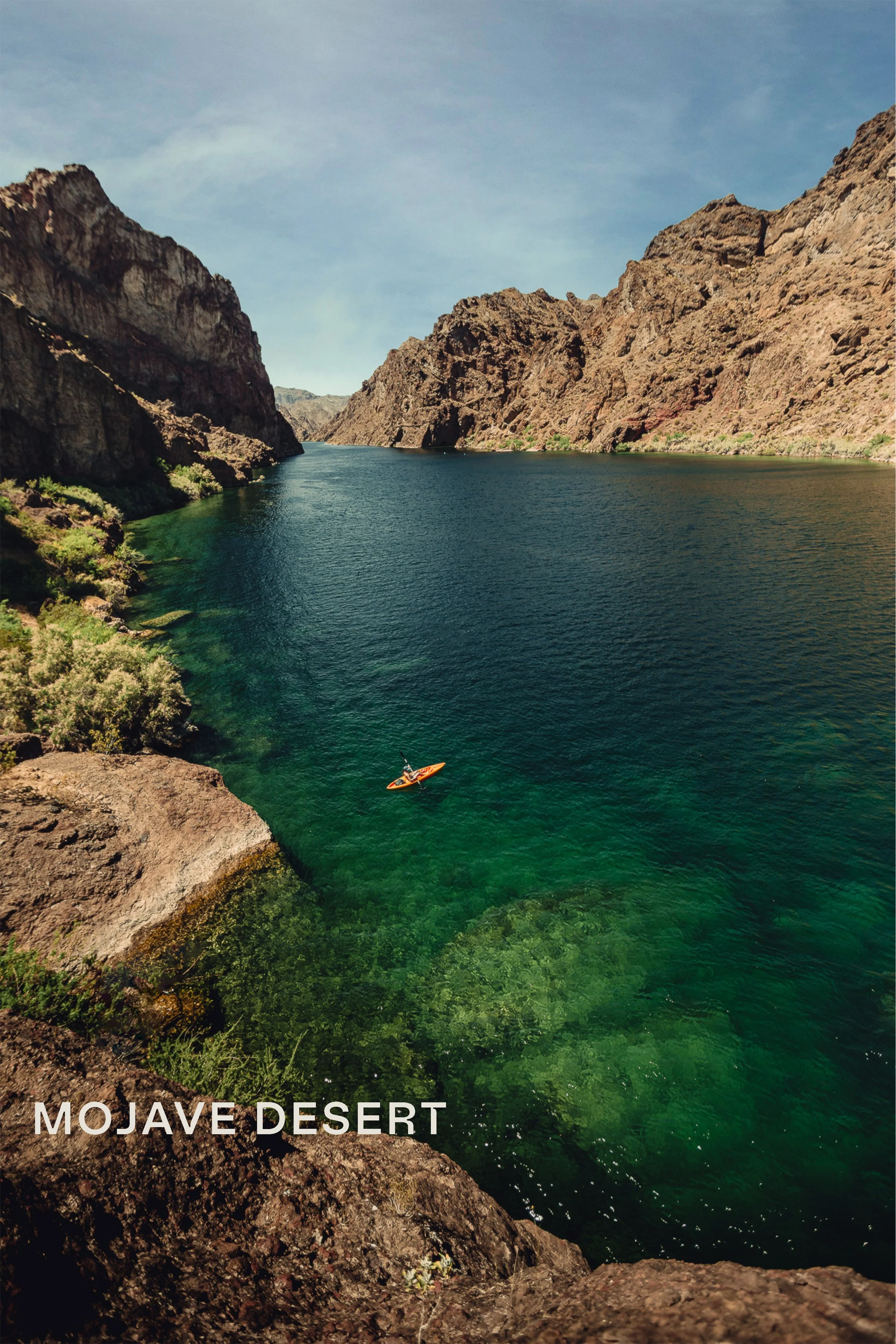 Kayaker in turquoise water at Emerald Cove on the Colorado River surrounded by dark canyon walls, Mojave Desert landscape photography by James Brasier