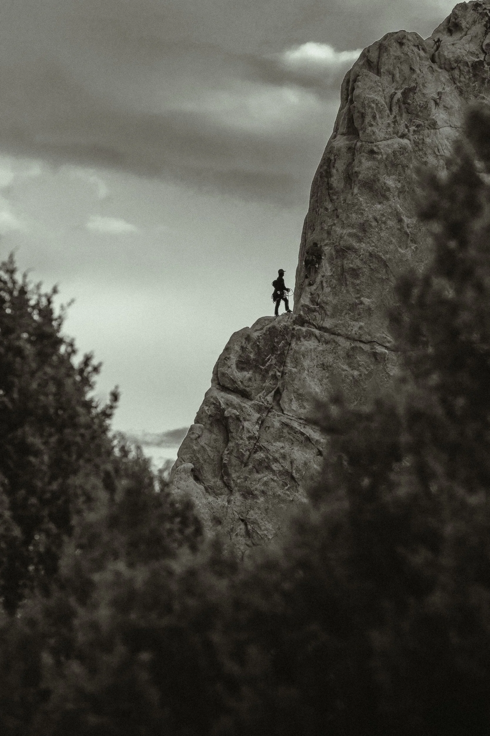 Rock climber silhouetted on a sandstone spire at Garden of the Gods in Colorado Springs, black and white outdoor adventure photography by James Brasier