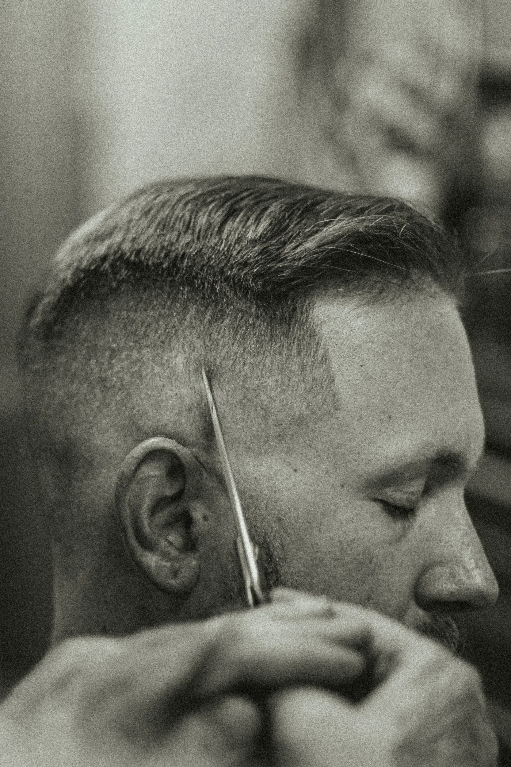Extreme close-up of scissors trimming along the hairline at Artisan Grooming Parlor in black and white, editorial detail photography by James Brasier