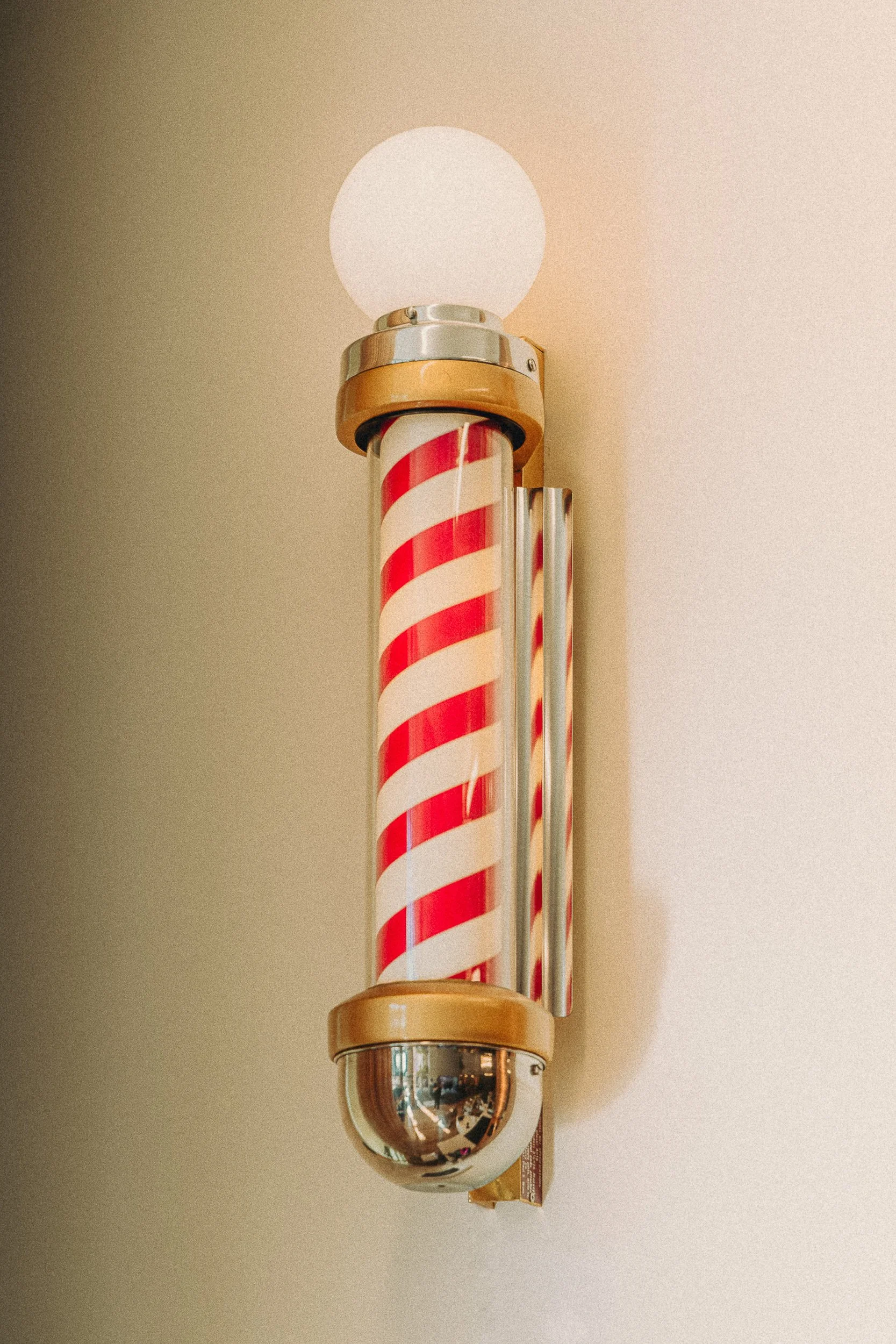 Classic red and white barber pole mounted on the wall at The Rosemont Barbers in Denver, editorial detail photography by James Brasier