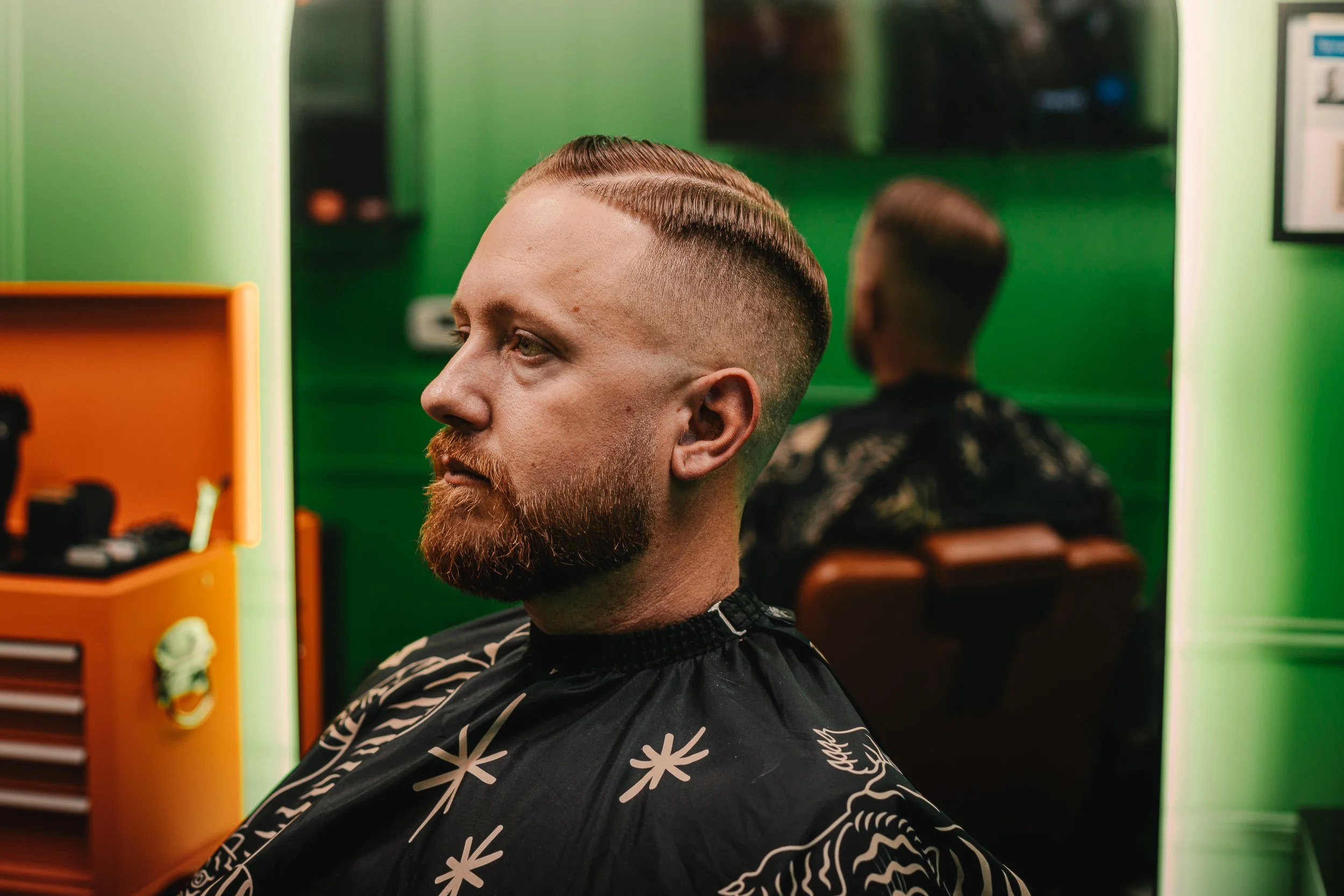 Client with finished haircut in profile view against green walls and orange toolbox at Artisan Grooming Parlor, commercial photography by James Brasier