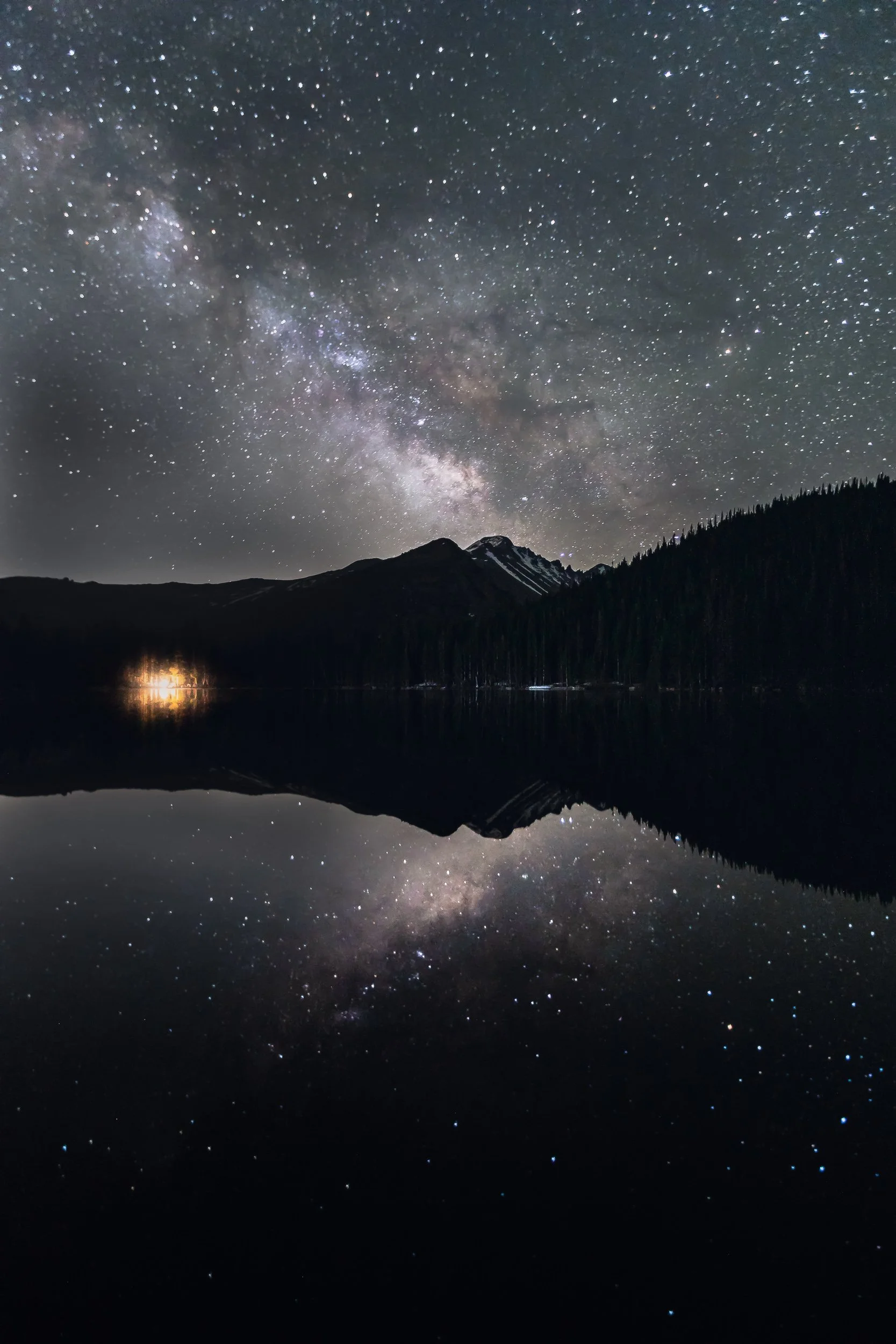 Milky Way reflected in Bear Lake with campfire glow at Rocky Mountain National Park, Colorado astrophotography by James Brasier