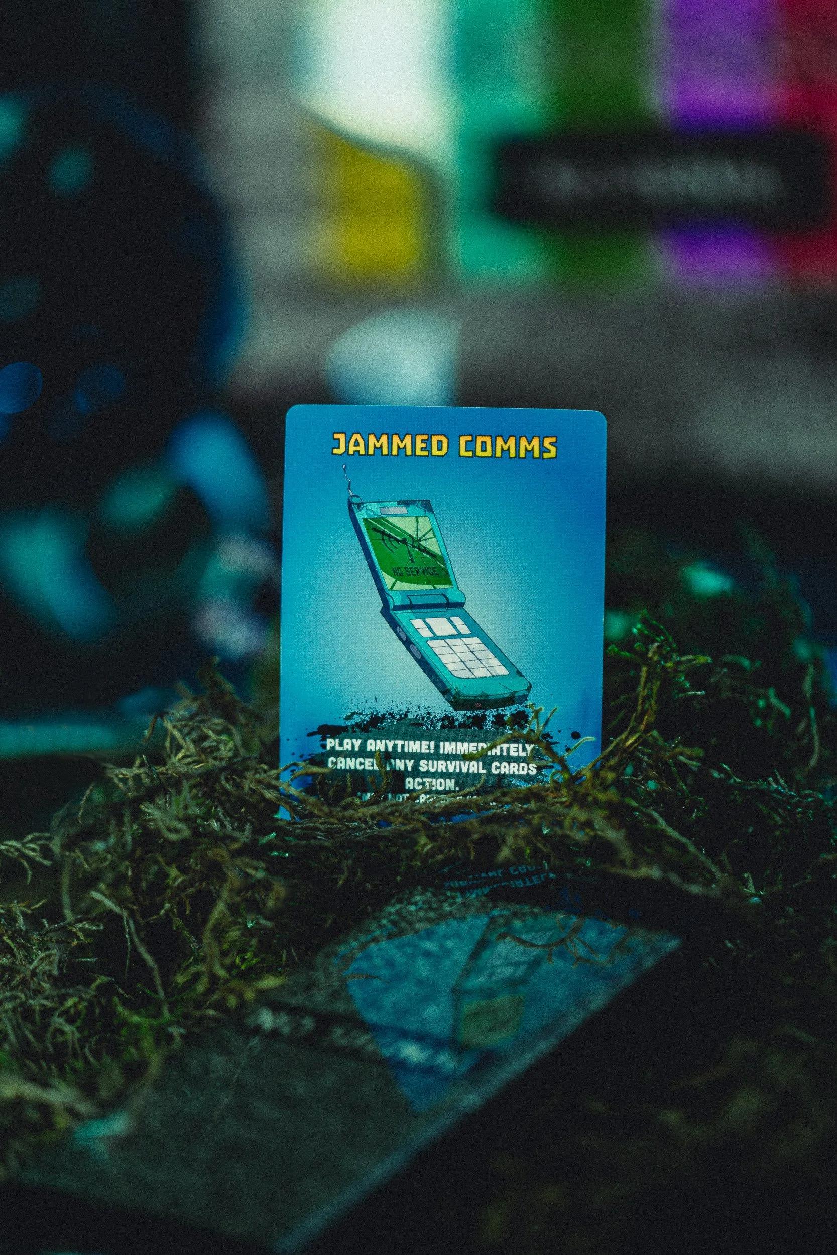 ZETA Survival Jammed Comms card on moss with blue and teal lighting, product photography by James Brasier