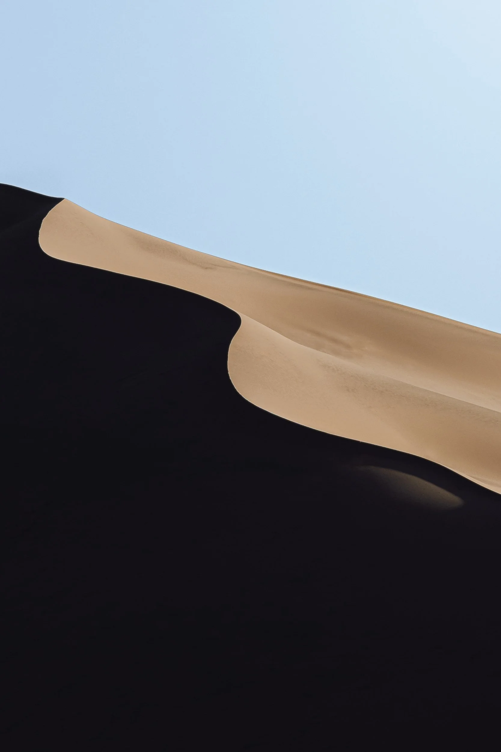 Sand dune ridge with dramatic shadows and S-curve against blue sky at Kelso Dunes in the Mojave Desert, desert landscape photography by James Brasier