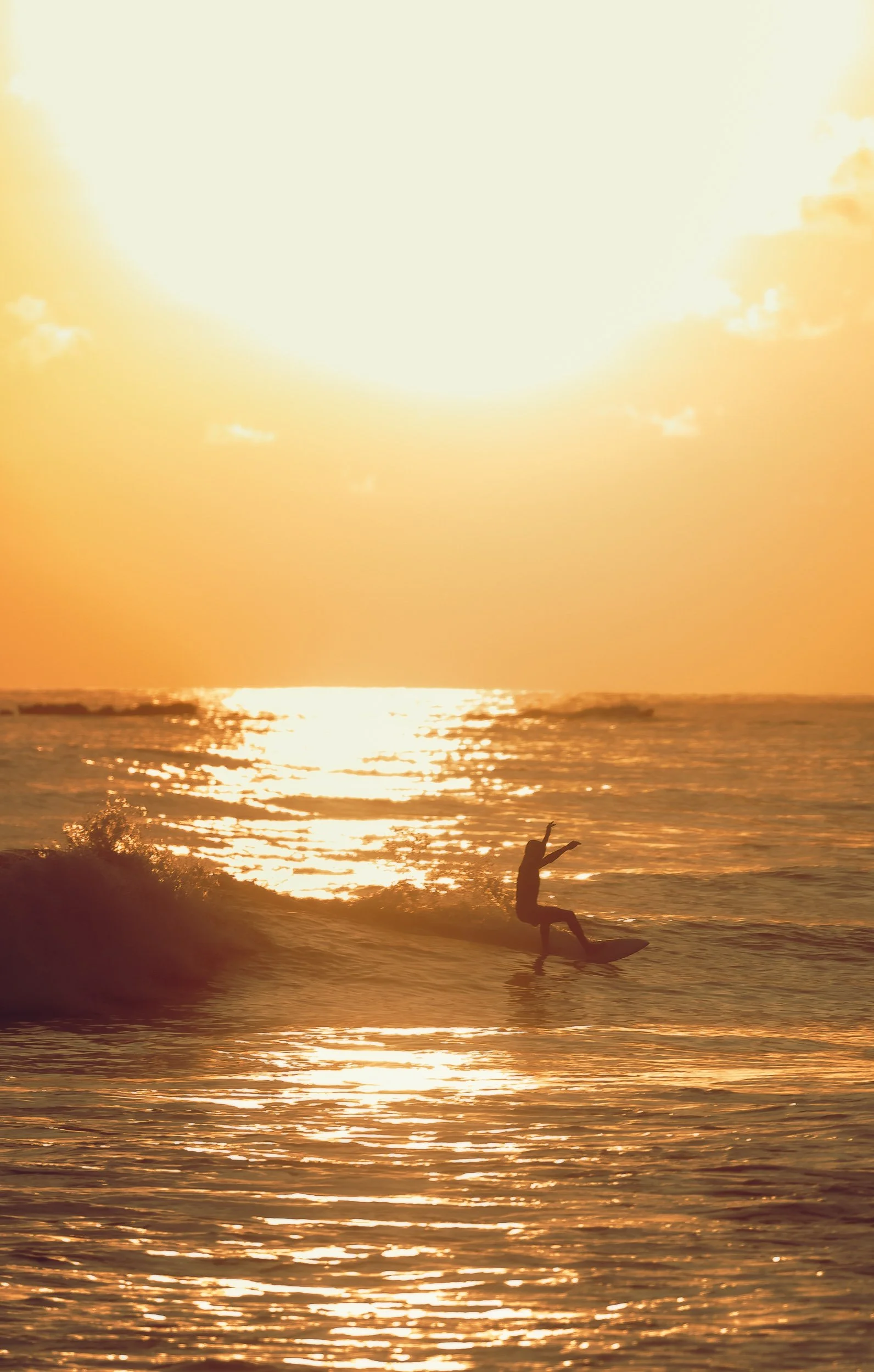 Surfer silhouetted against golden sunset walking into the waves at Playa Guiones Costa Rica, sunset surf photography by James Brasier
