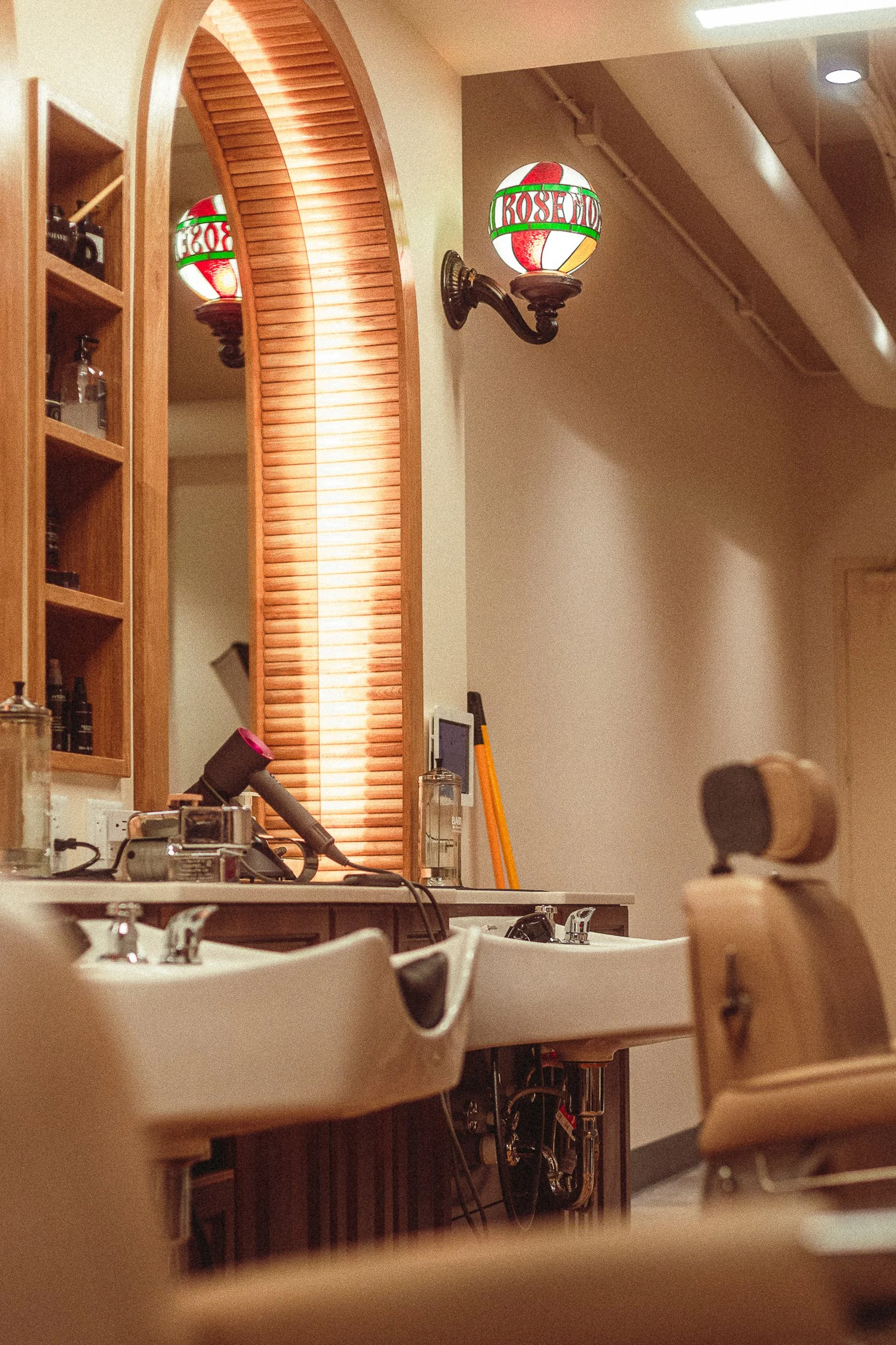 Stained glass Rosemont globe light fixture above a barber station with arched mirror, architectural detail photography by James Brasier