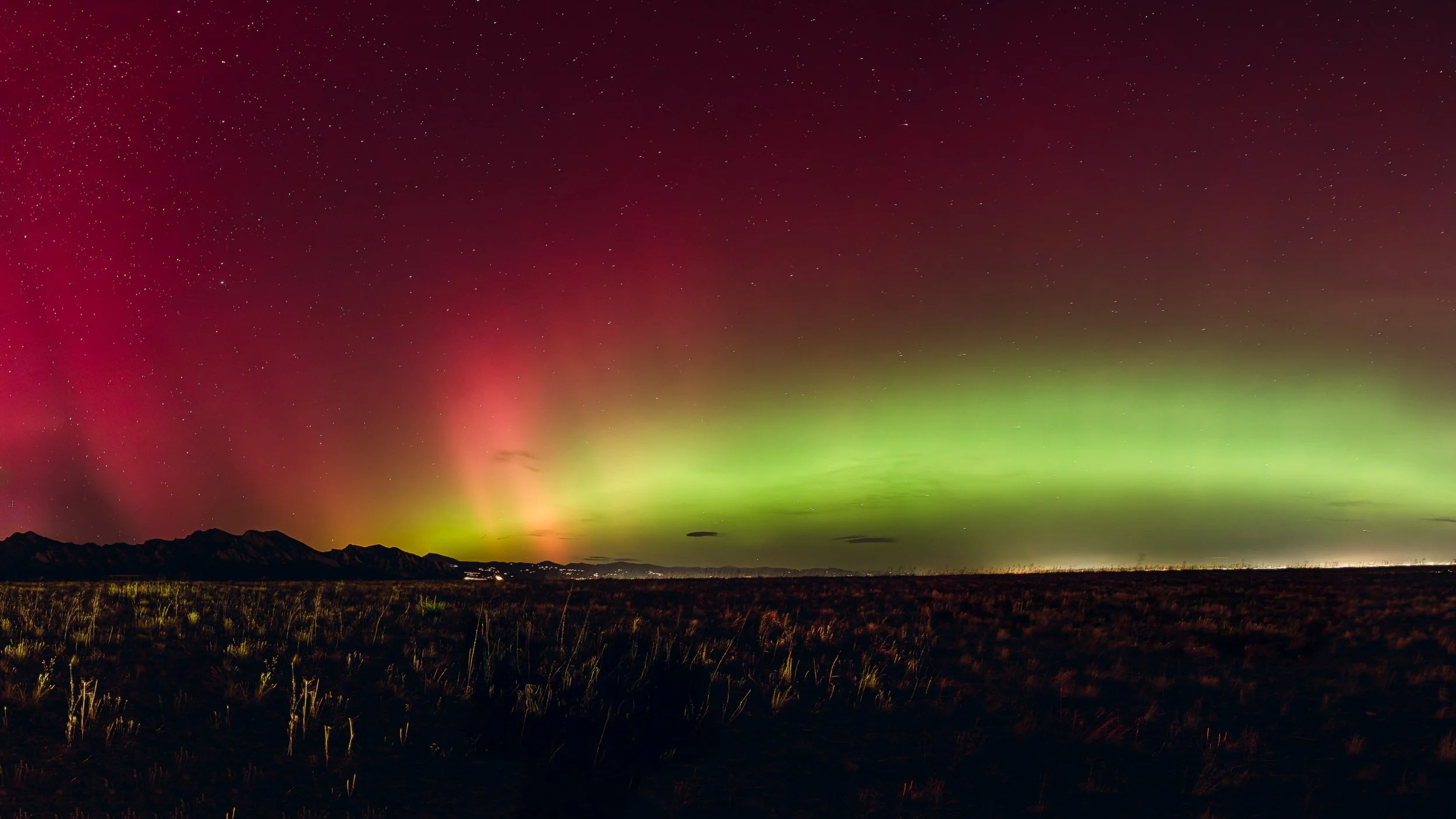 Aurora borealis with pink and green bands over the Front Range mountains near Boulder Colorado, night sky photography by James Brasier