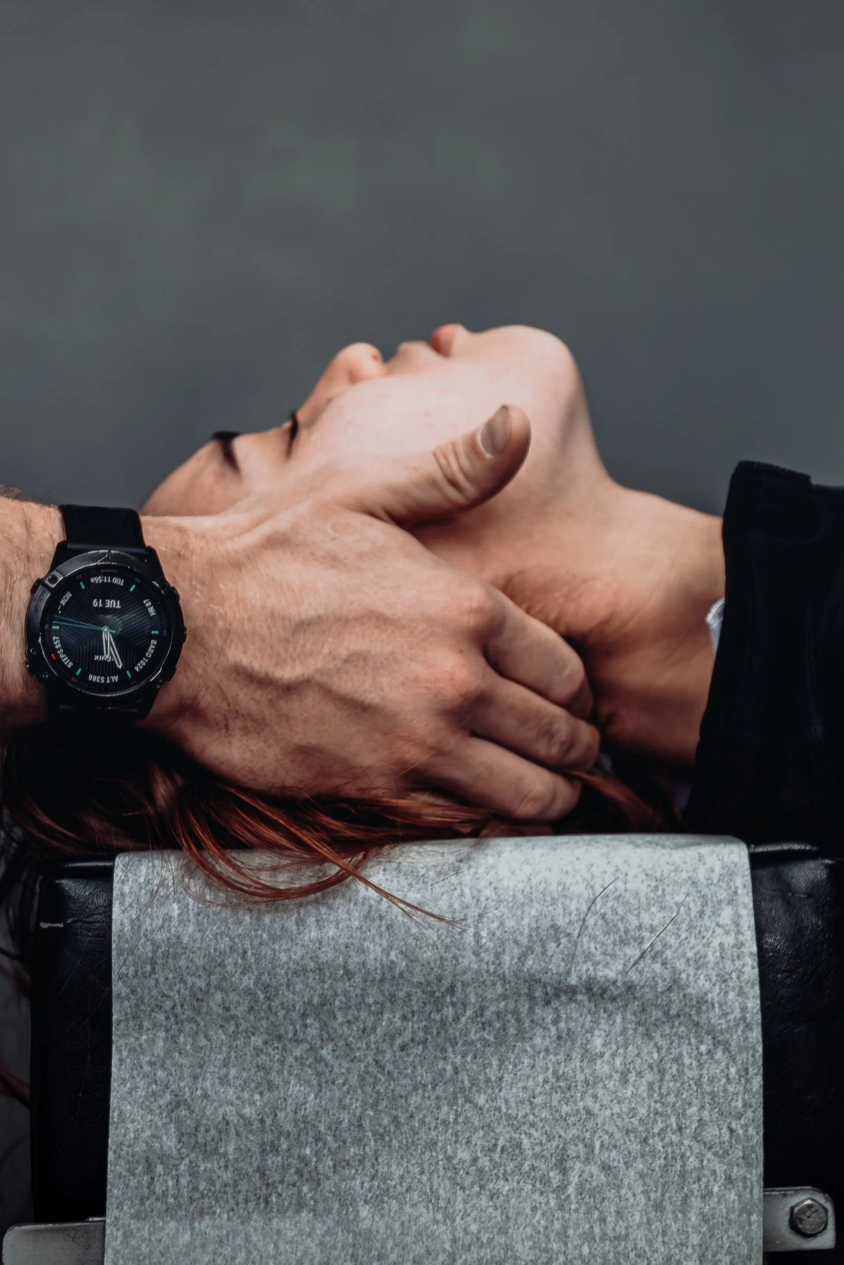 Hands performing chiropractic cervical adjustment with watch detail at Square One Health, commercial photography by James Brasier