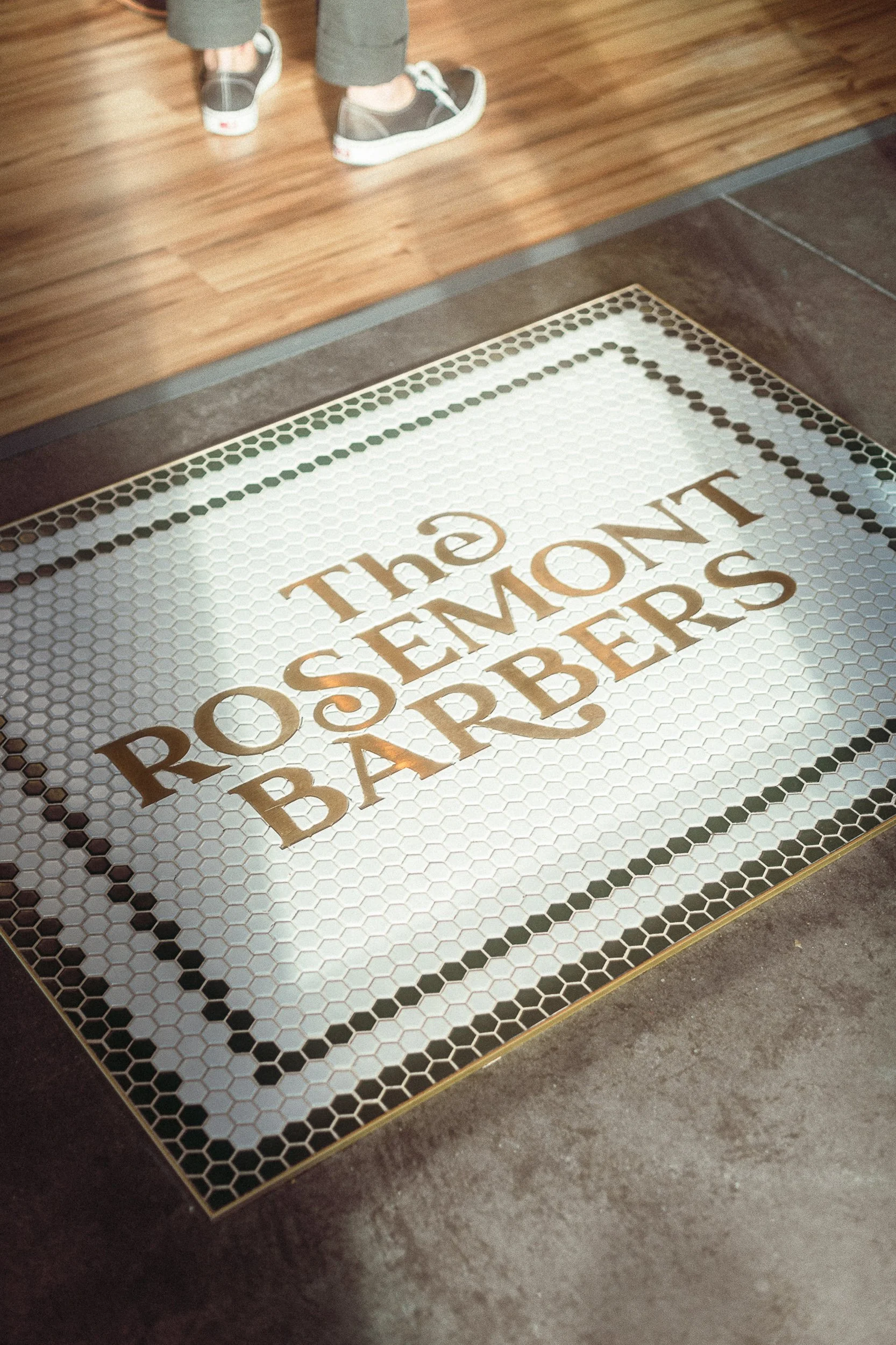 Custom hexagonal mosaic tile floor with The Rosemont Barbers logo at the entryway in Denver, commercial interior photography by James Brasier