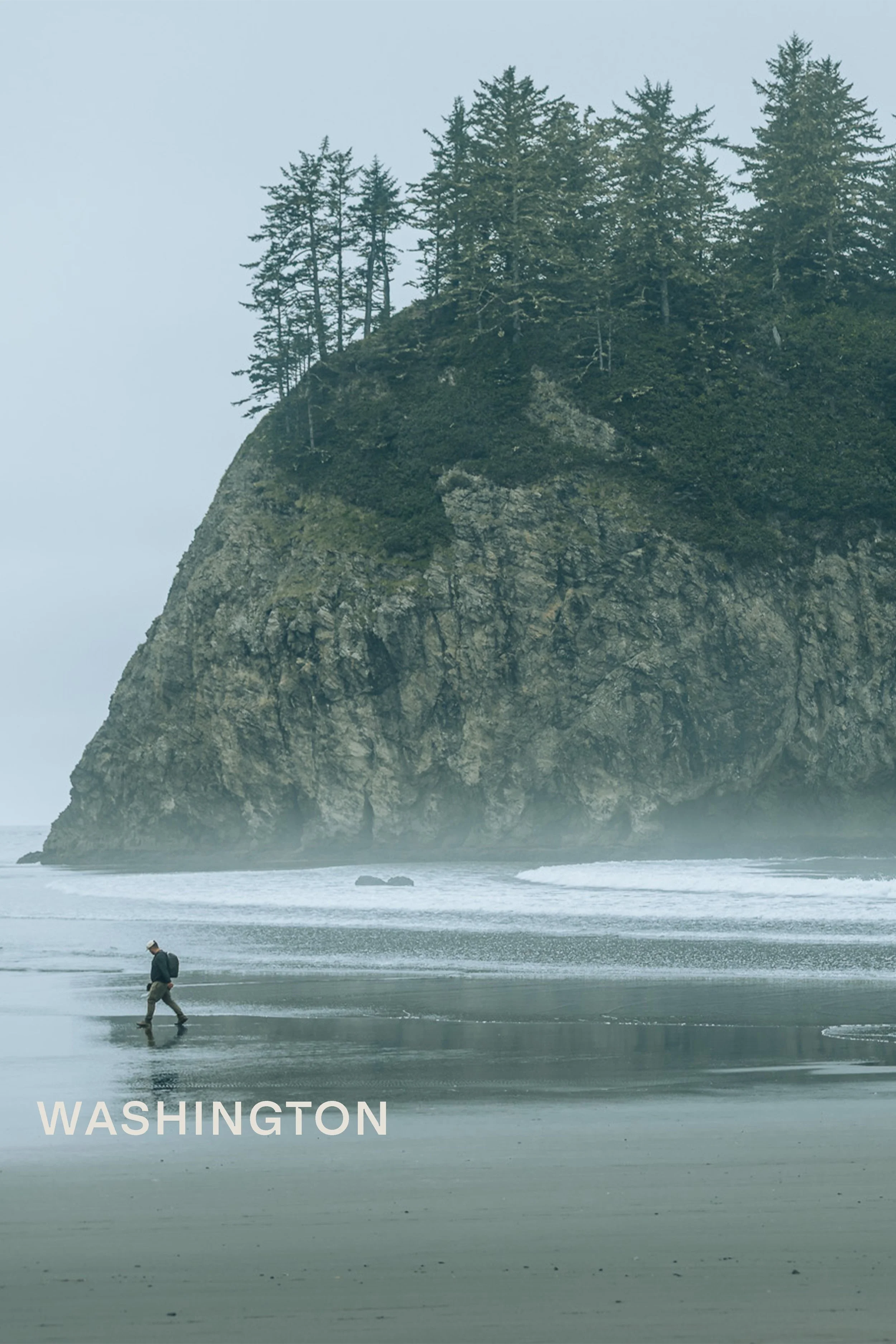 Hiker walking on foggy beach toward sea stack on the Olympic Peninsula, Washington state landscape photography by James Brasier