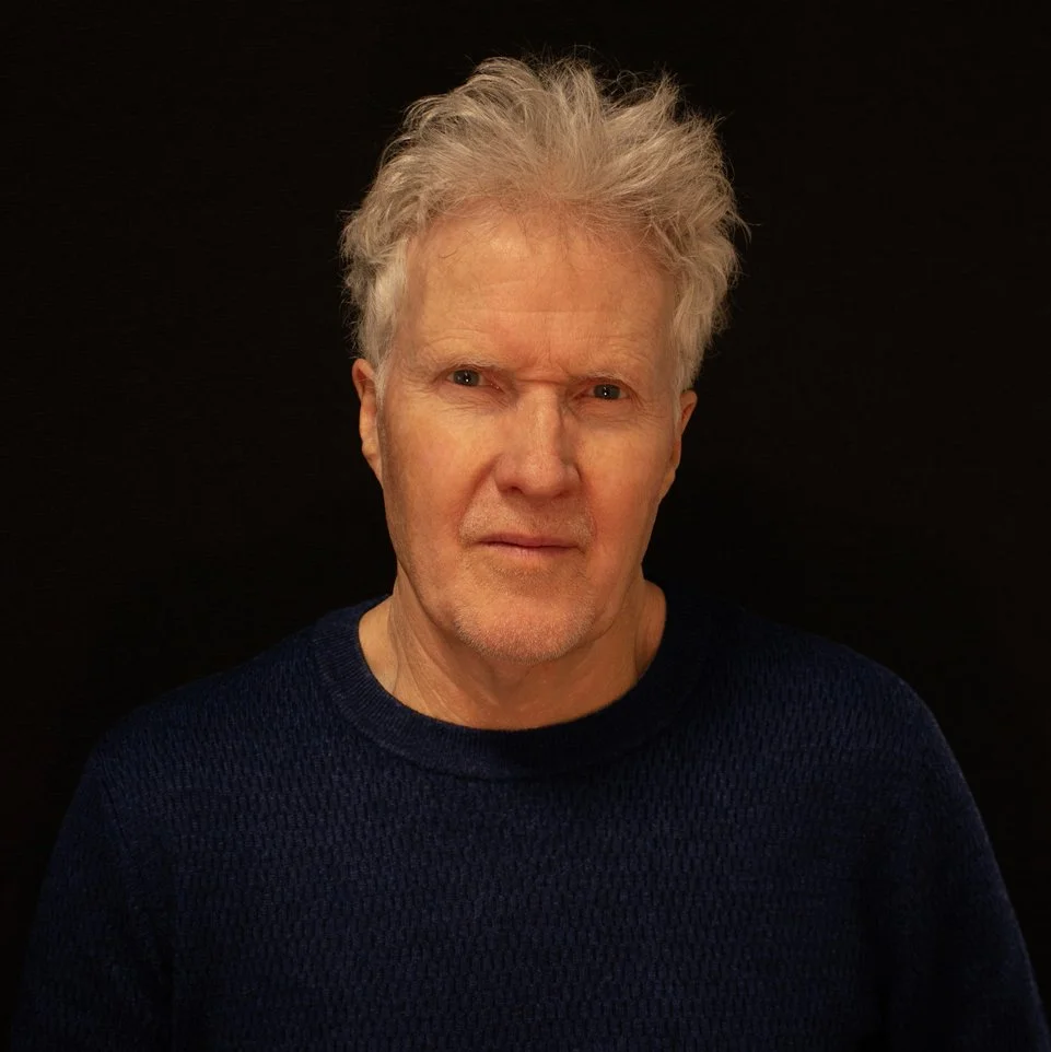Color portrait of Steve Pilcher wearing a dark blue sweater against a black background.