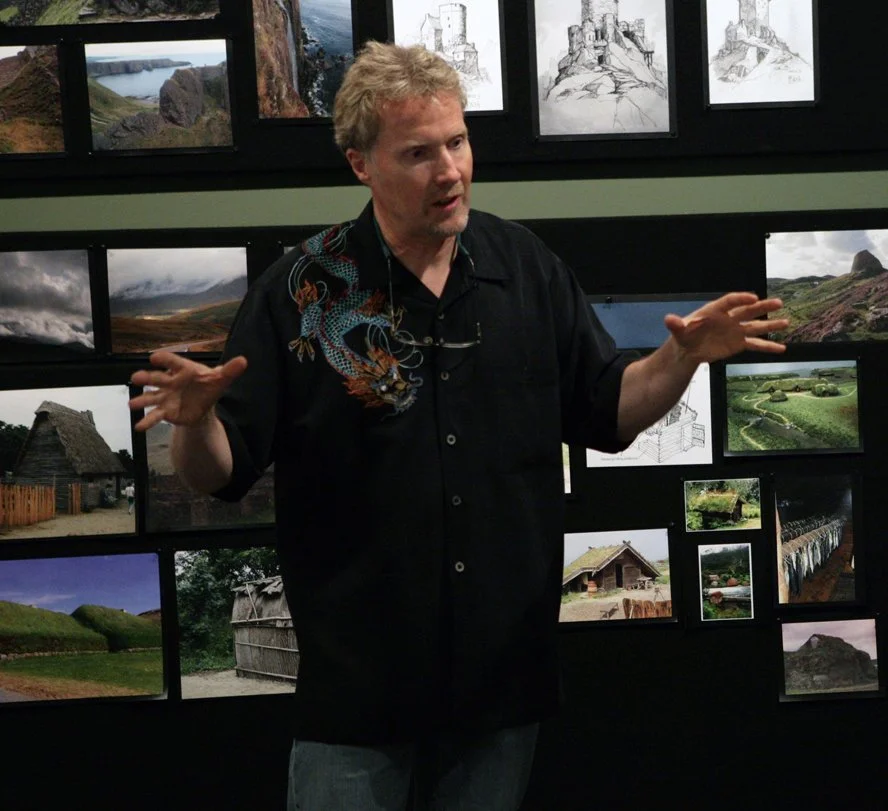 Color photo of Steve Pilcher in a black shirt with hands raised at Pixar Animation Studios pitching ideas for the film “Brave.”