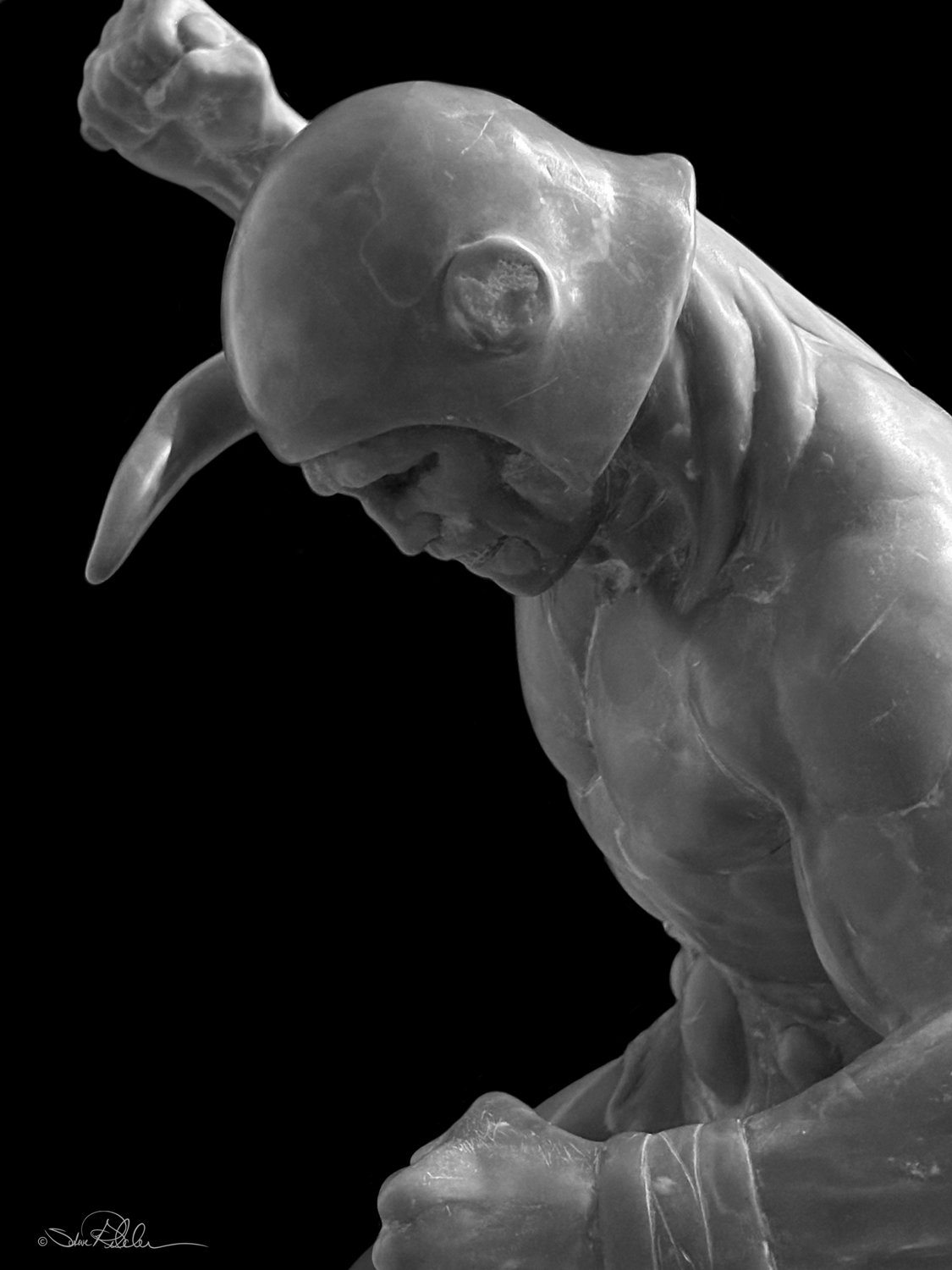 Sculpture in grey epoxy resin of muscular barbarian warrior with broken helmet missing a horn from a battle.
