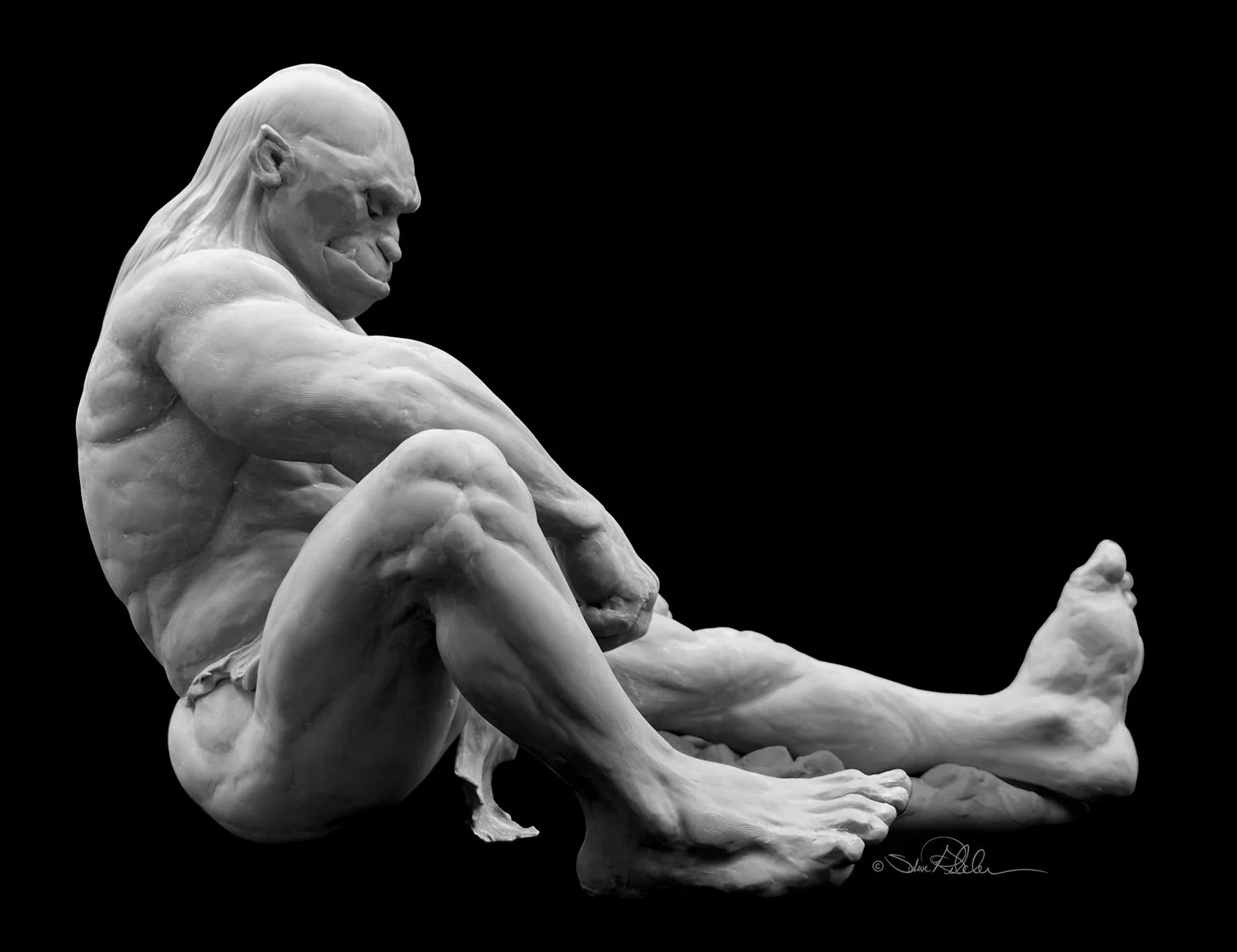 Sculpture in grey epoxy resin of a muscular sleeping giant resting against rocks and boulders with one arm resting on his leg and the other on a boulder in profile.