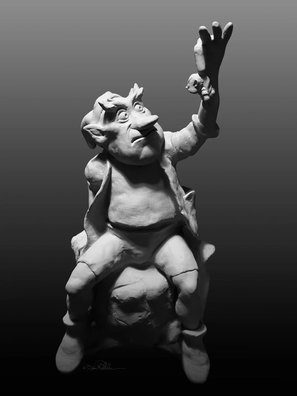 Sculpture in grey clay of troll sitting on an old tree stump holding a small elf like character up in the air by his tiny over coat.