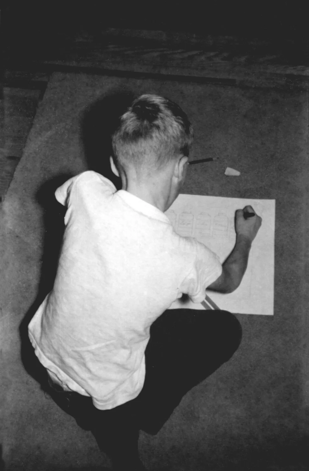 Black and white photo of Steve Pilcher at age 7, starting a drawing while sitting on the floor.