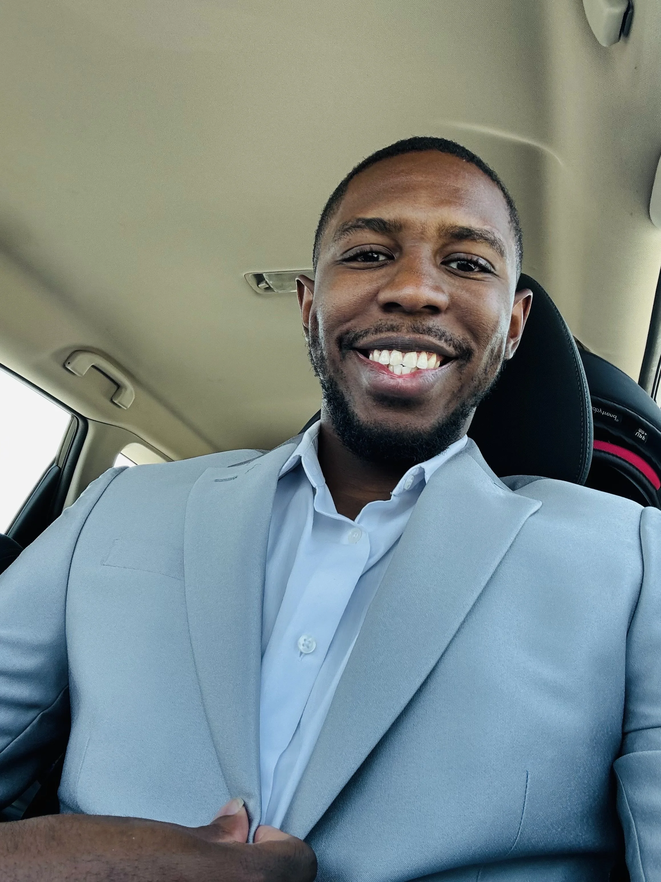 Portrait of a woman with shoulder-length black hair, glasses, and a black top, smiling against a plain white background.