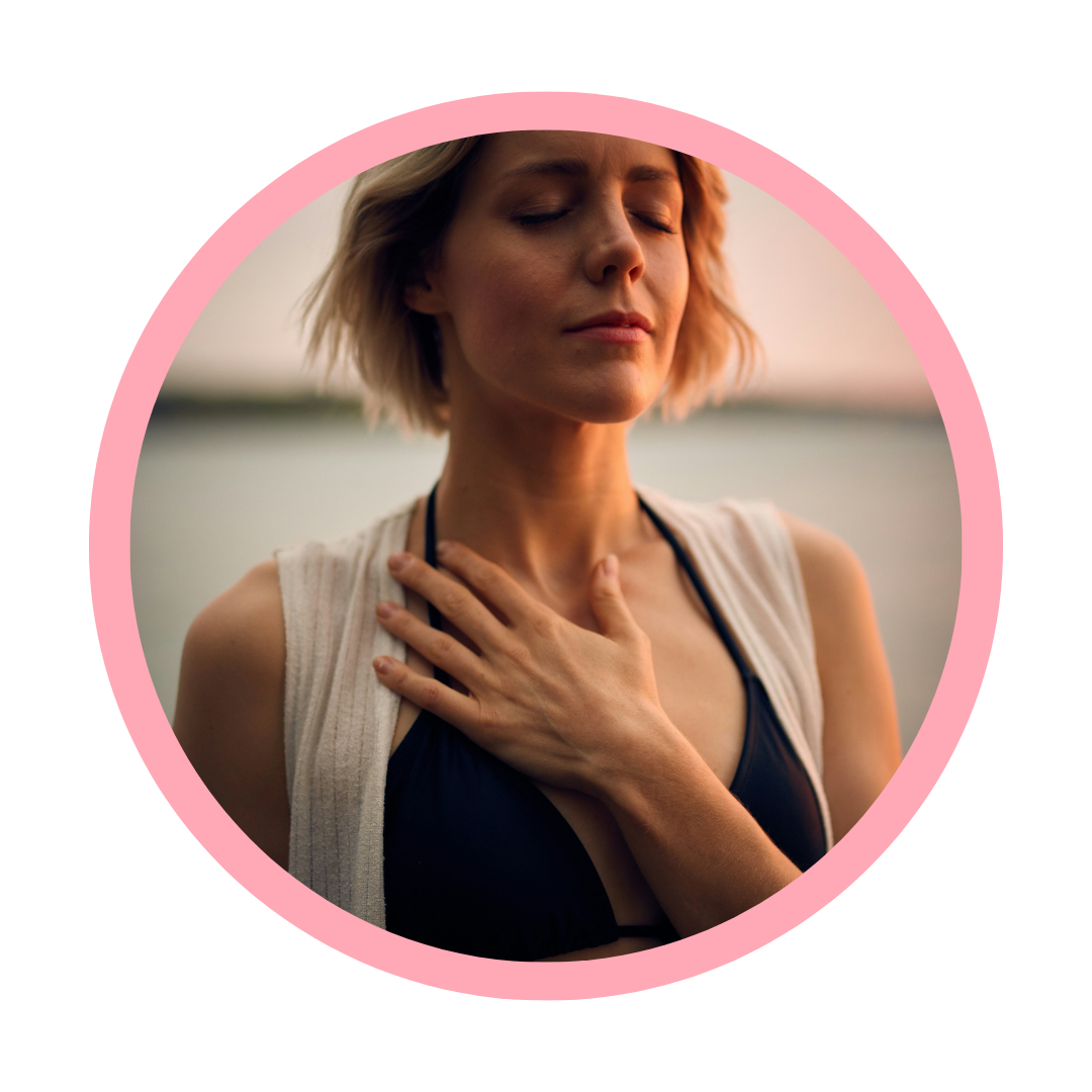 A woman with short blond hair, eyes closed, holding her hand on her throat, appearing to be experiencing discomfort or pain outdoors during sunset.