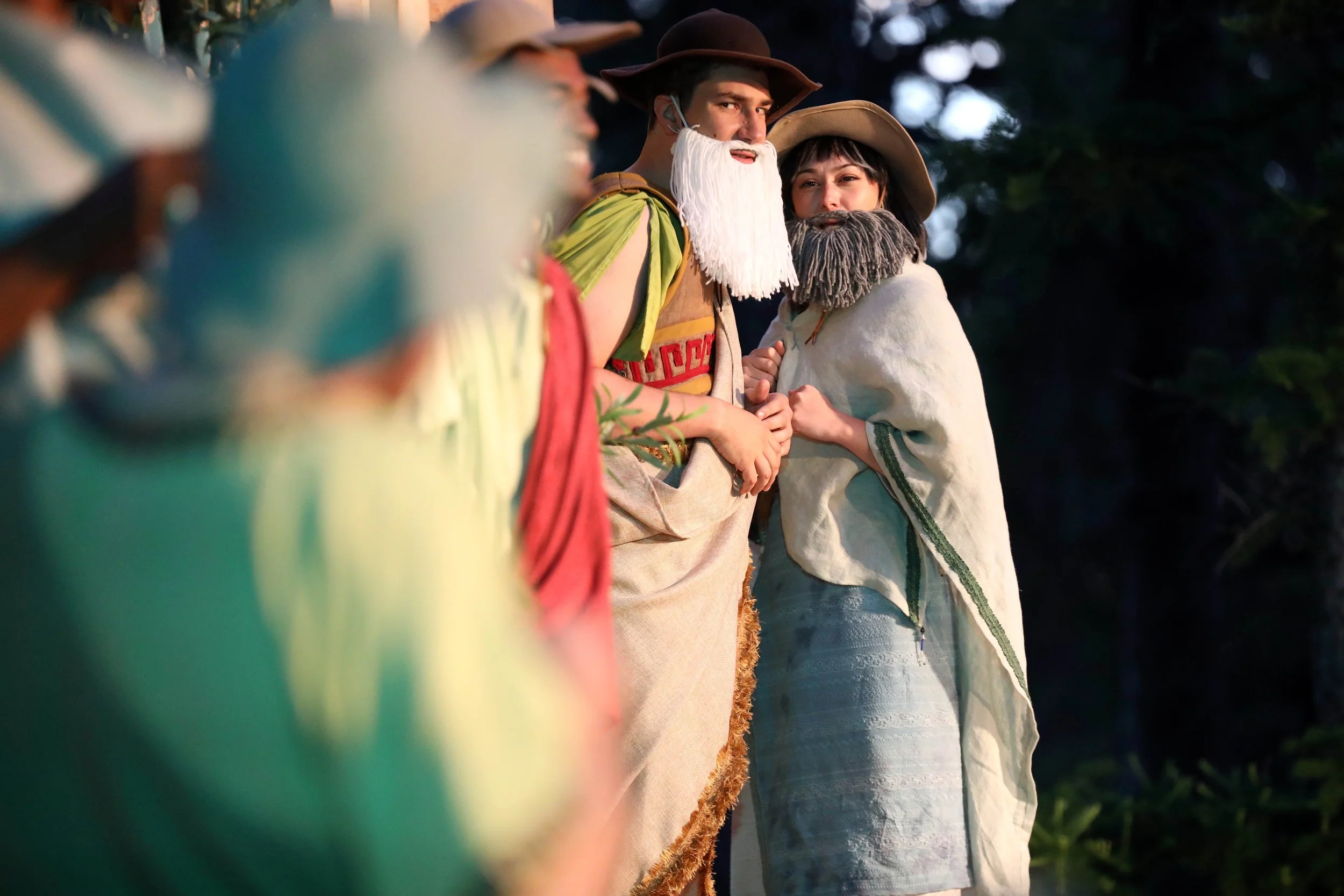 Emily Michelle Walton as Camillo and Calvin Adams as Polixenes in disguise in The Winter's Tale at Montana Shakespeare in the Parks, standing outdoors in Mycenaean-inspired costumes with false beards.