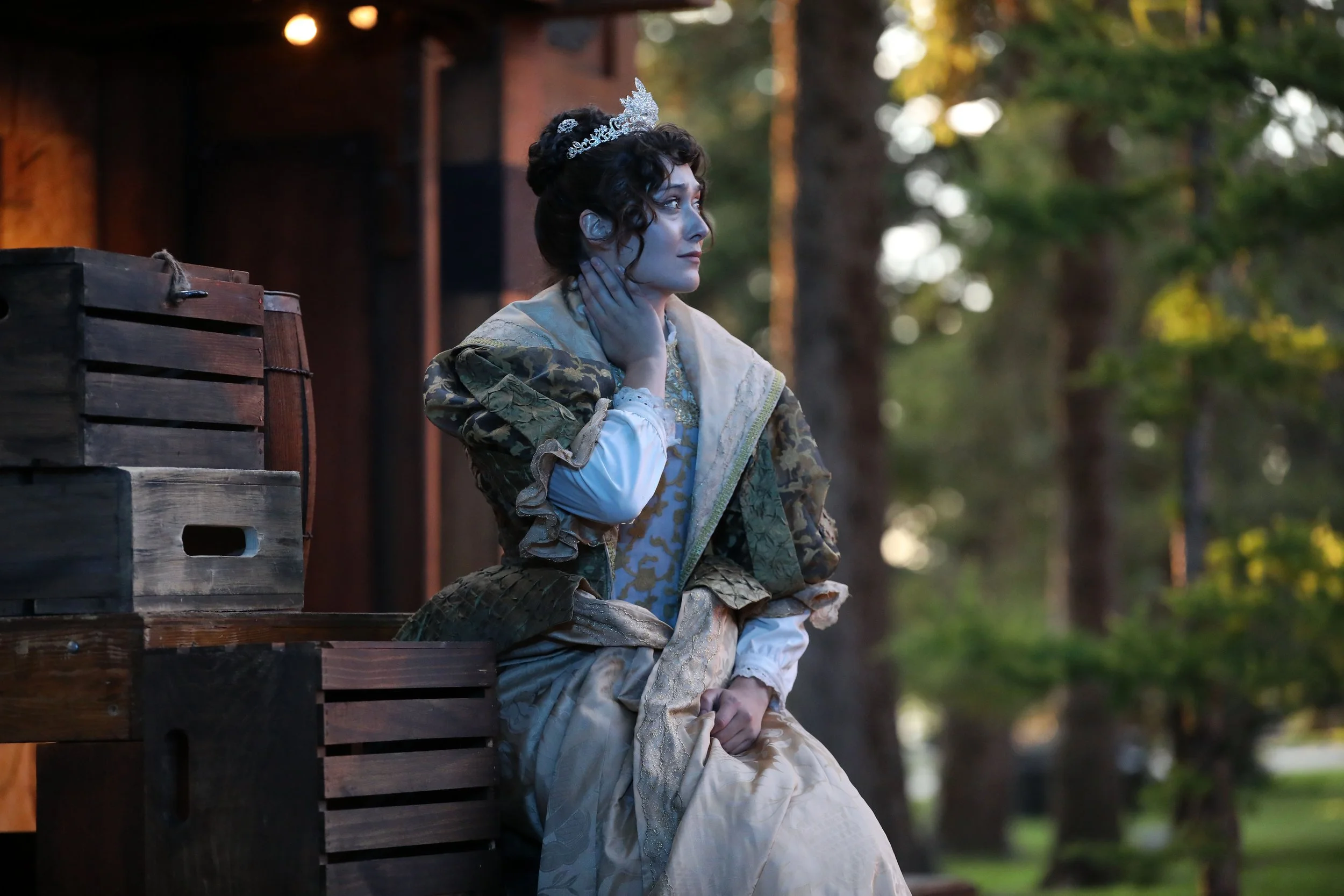 Emily Michelle Walton as Queen Anne in The Three Musketeers at Montana Shakespeare in the Parks, wearing a crown and seated thoughtfully onstage.
