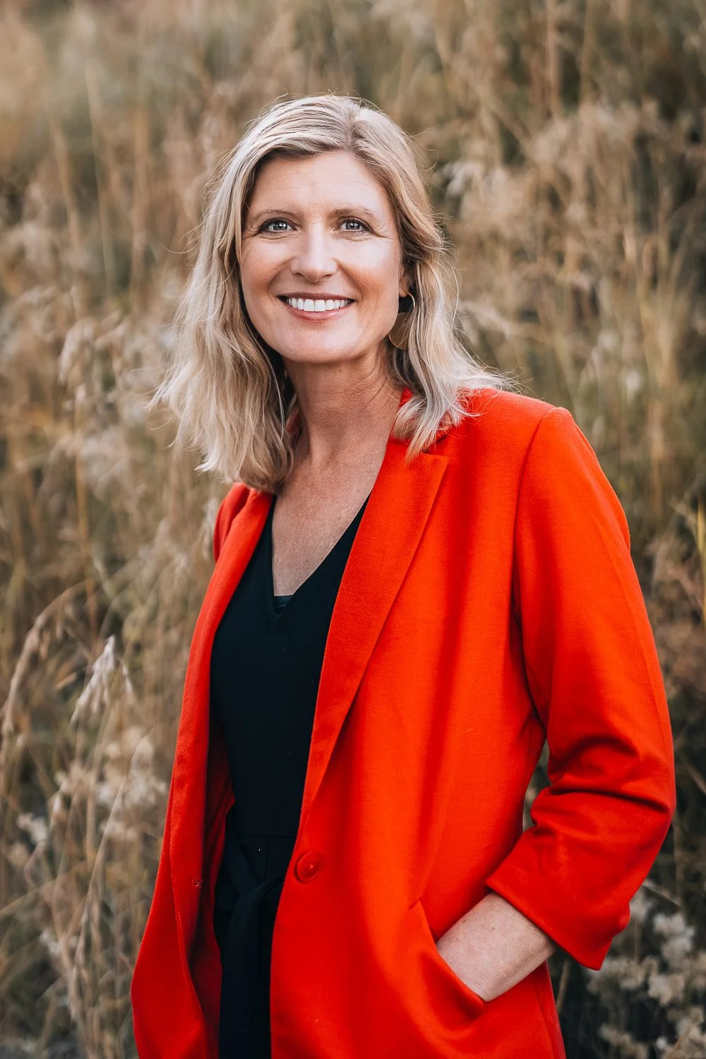 A portrait of a woman with blonde hair, wearing a red blazer