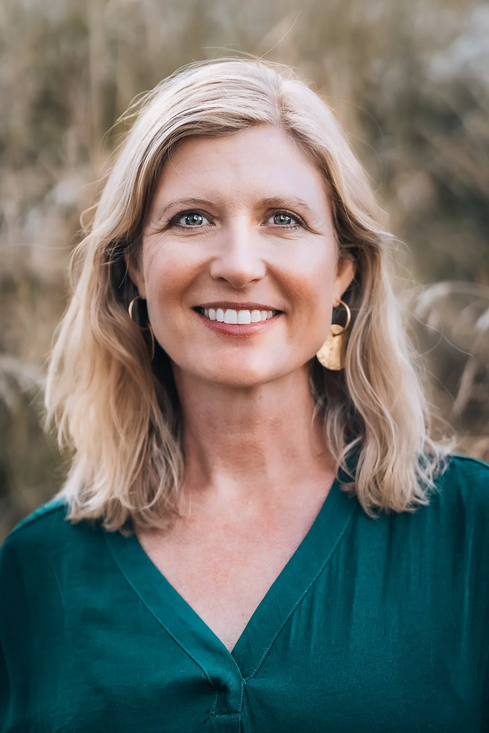 A professional headshot of a smiling woman with blonde hair