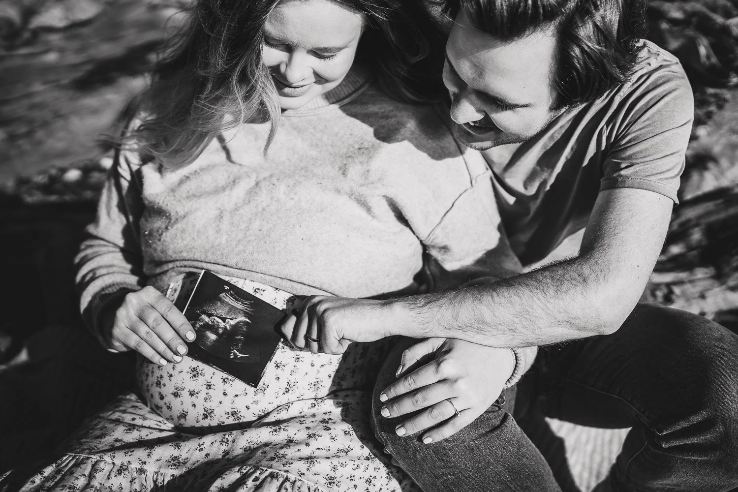 Maternity photo of parents holding and watching their baby's ultrasound photo
