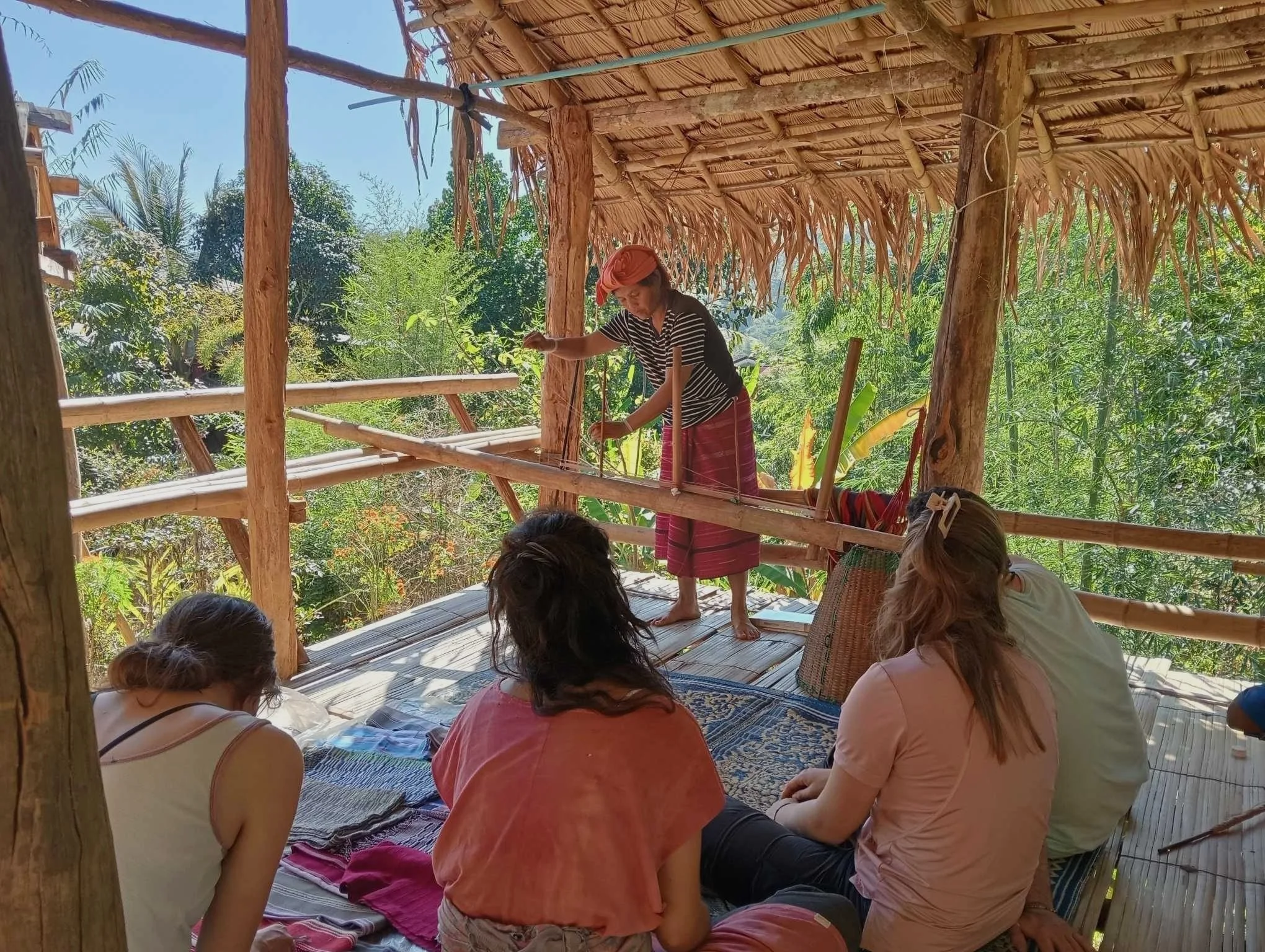 Woman in wooden hut showing a group of female travellers traditional wood crafting techniques