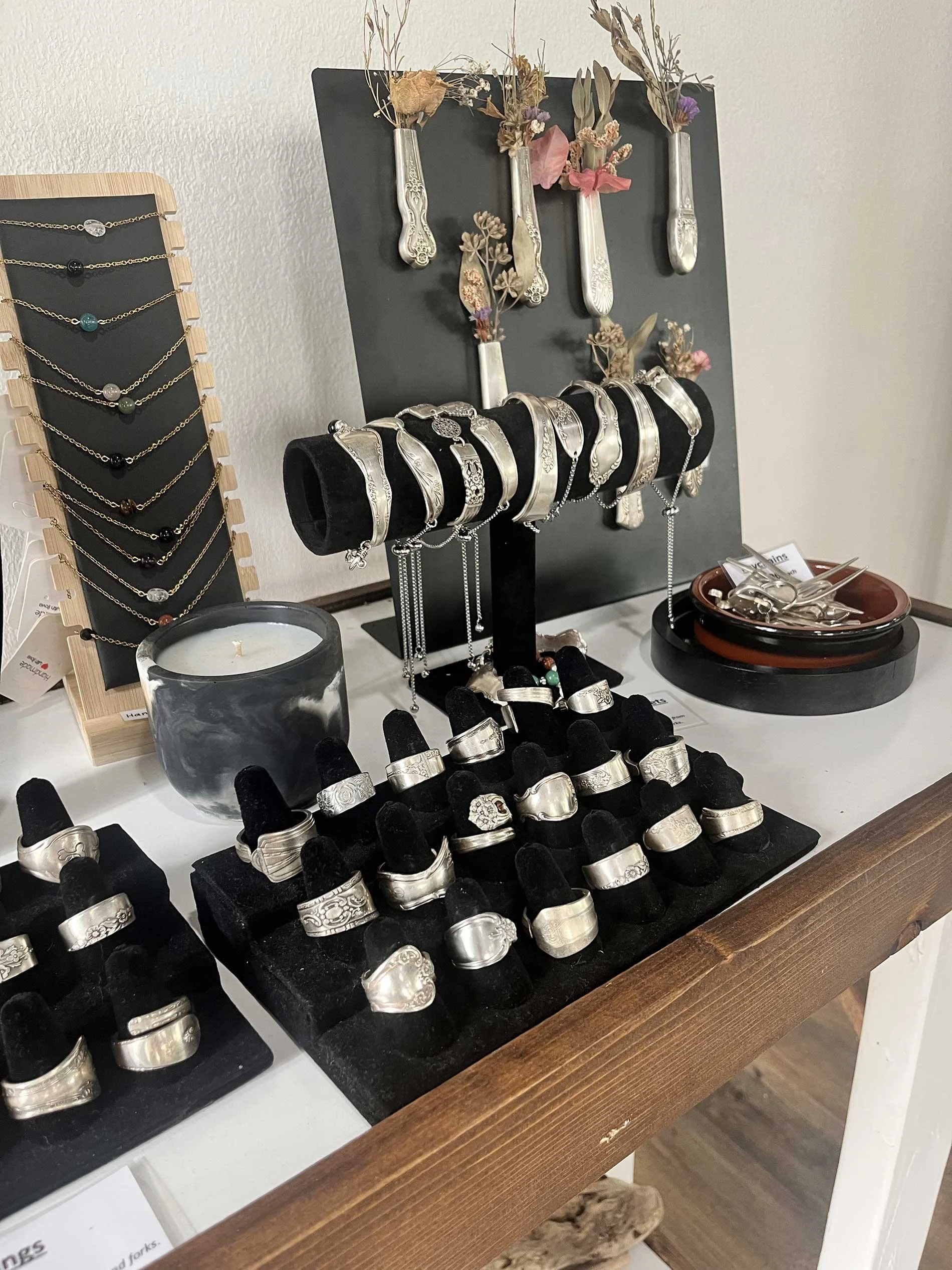 Display of jewelry and accessories including earrings, a clutch purse, and a hat on a wooden shelf