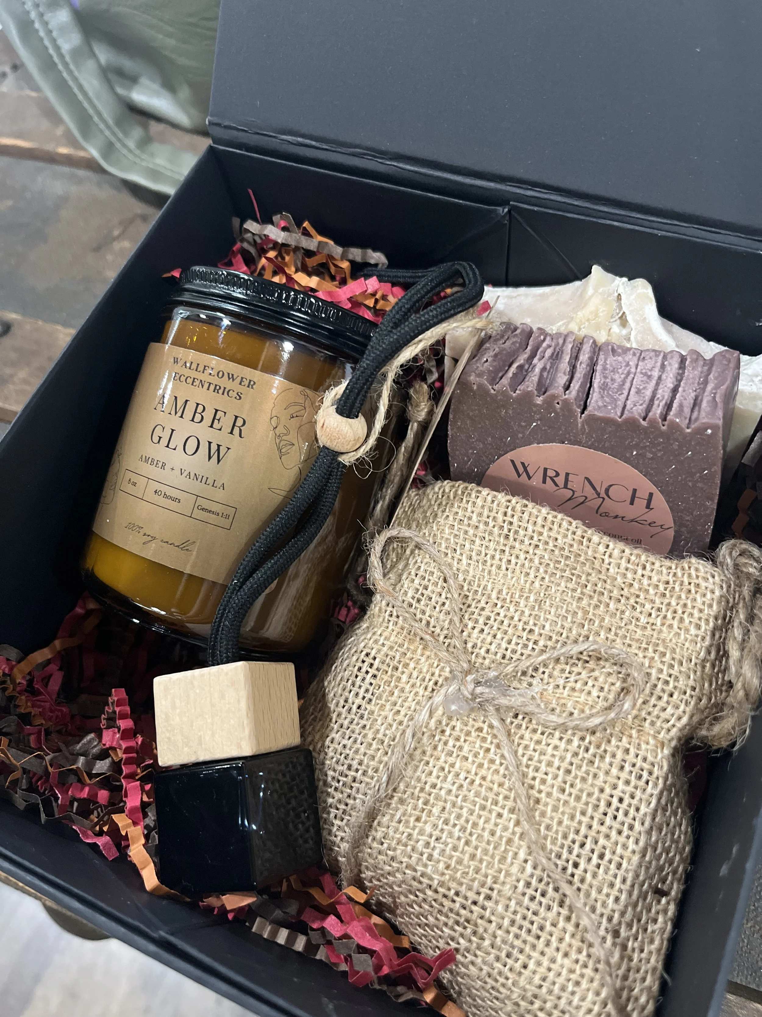 A decorated Christmas tree with a pink sequin cowboy hat at the top. The tree has various ornaments including a snowman, a wooden plaque that says 'Uppland California,' a reindeer, a white ball, and an 'Home is where the dog is' ornament. The tree is illuminated with small yellow lights. In the background, a retail store with wooden shelves and a chalkboard sign can be seen.
