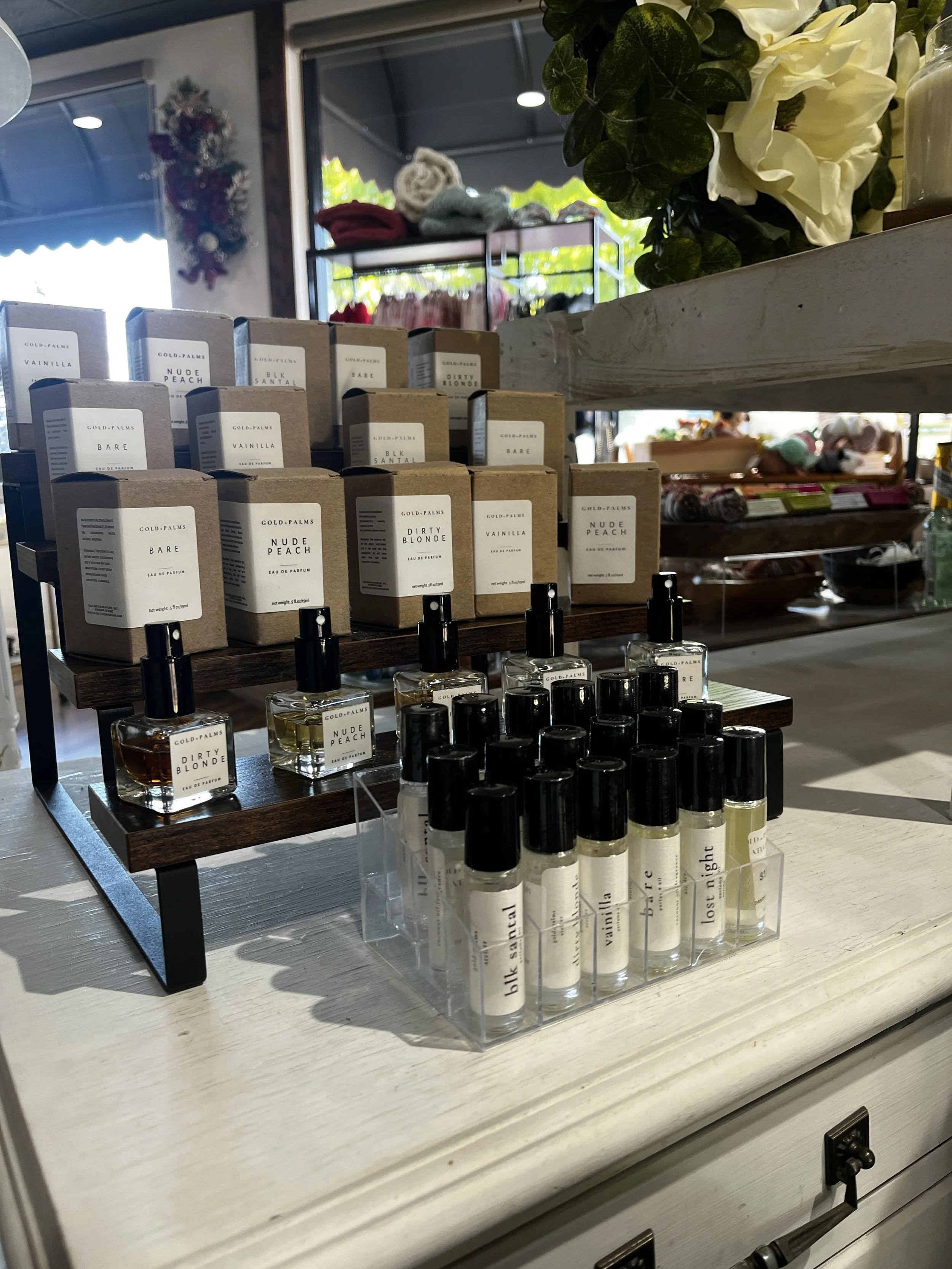 Display of holiday decorations, including ceramic mugs with Christmas designs, a small Christmas tree figurine, starfish and driftwood wall art, a tiny white artificial Christmas tree, and other seasonal ornaments on wooden and glass surfaces.