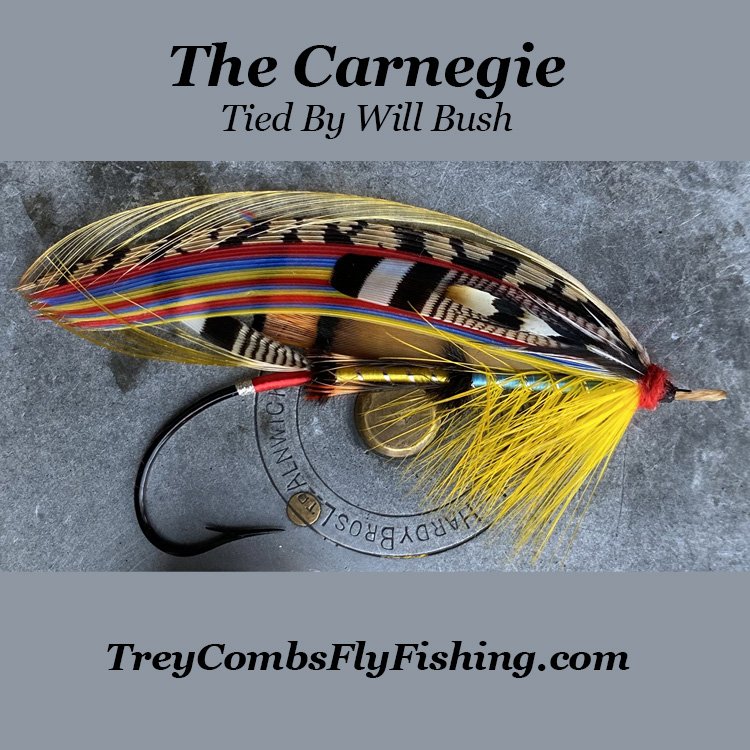 A classic Victorian Carnegie full-dress salmon fly, developed by George Kelson and tied by Will Bush, featuring a yellow and light blue silk body with mixed feather wings.