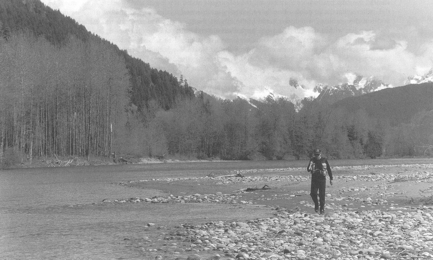 Trey Combs walking along a gravel bar beside a river, illustrating steelhead holding water and winter fishing conditions