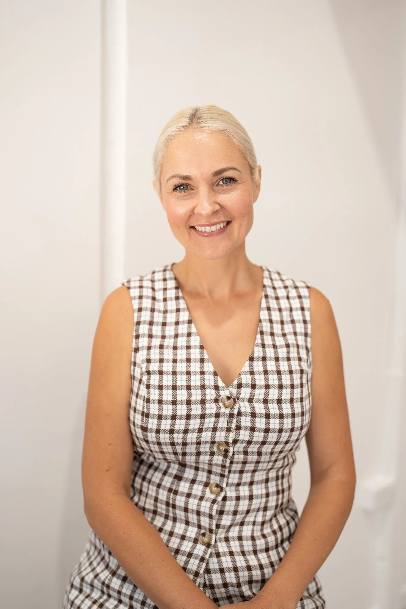 Smiling woman in checkered dress against white background