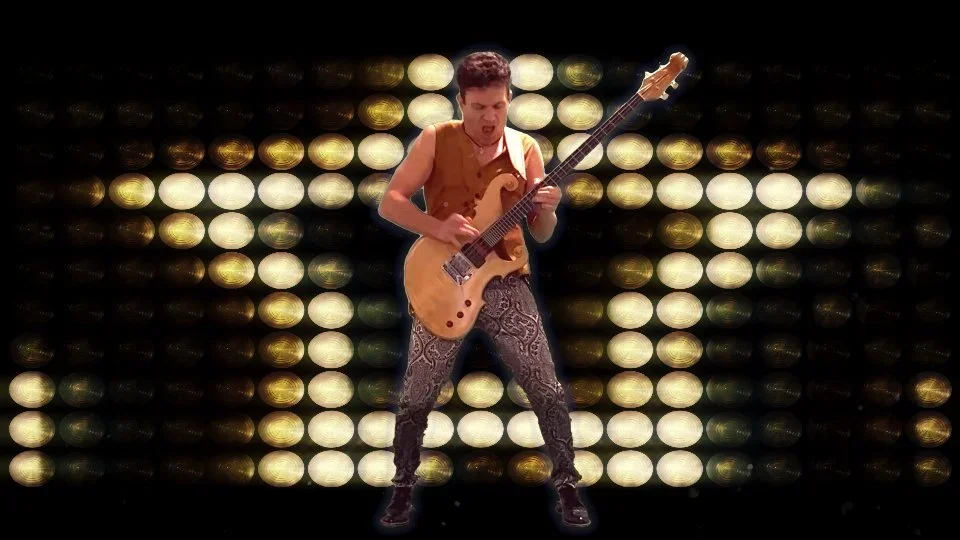 A man playing an electric guitar on stage with a background of bright, circular, golden and white lights.