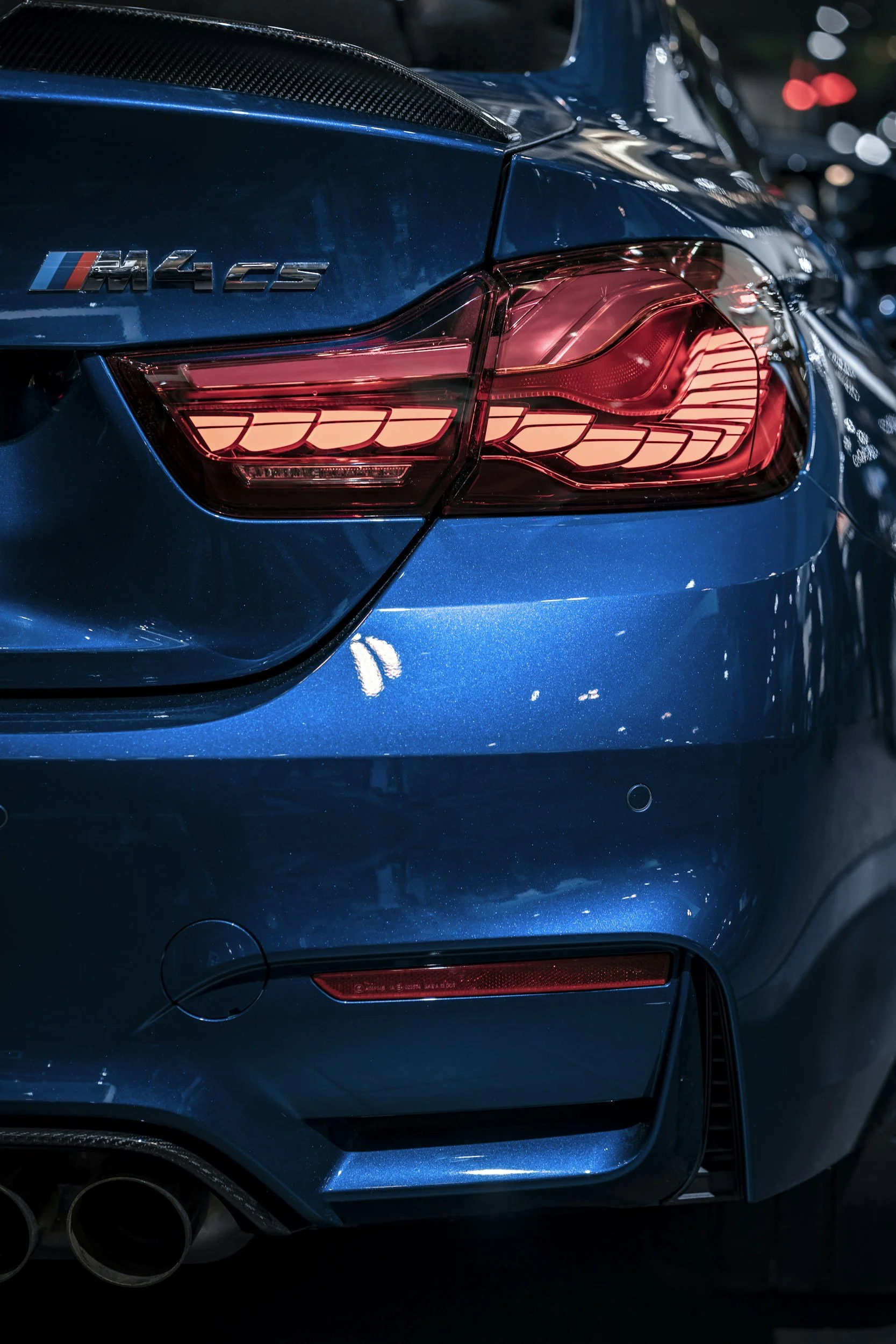 Close-up of the rear of a blue BMW M4 CS vehicle, showing the taillight and M4 CS badge.
