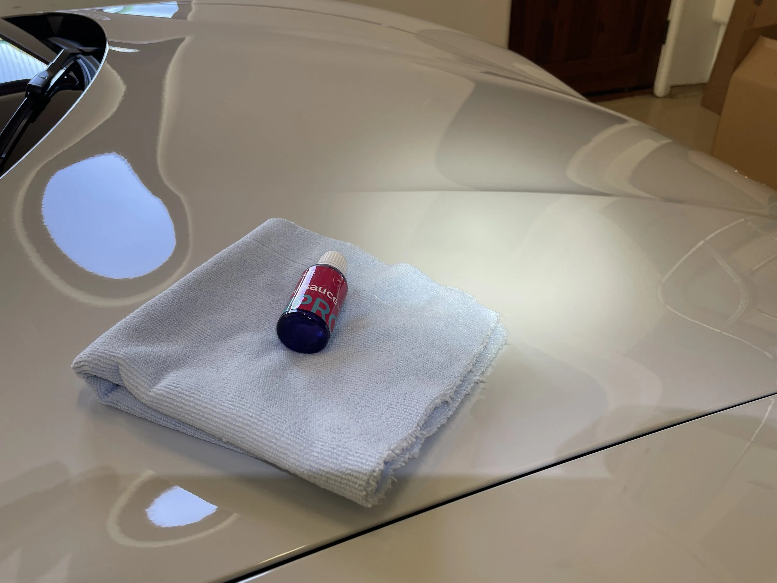 A white cloth and a small bottle of car detailing spray are placed on the hood of a car.