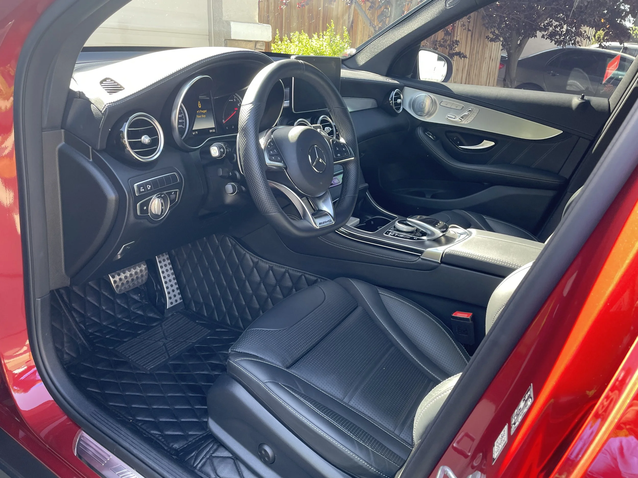 Interior of a red luxury Mercedes-Benz car, showing black leather seats, a dashboard with digital displays, a steering wheel with controls, and silver accents.