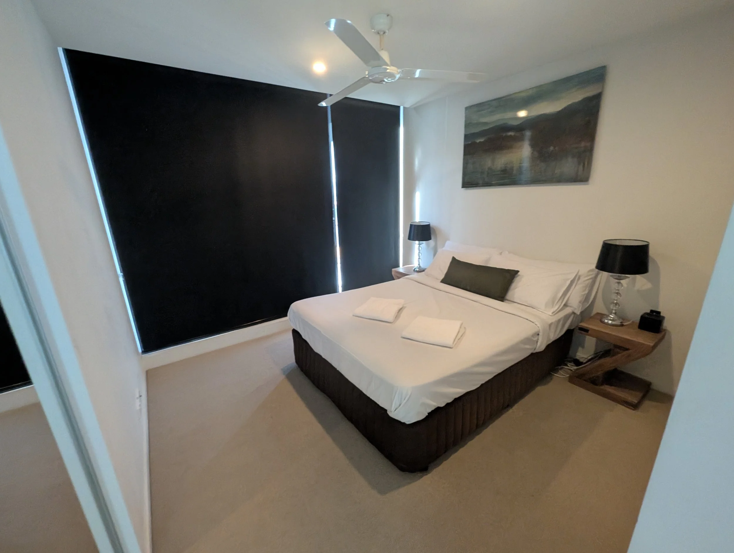 Clean neat bedroom with folded towels and tucked sheets