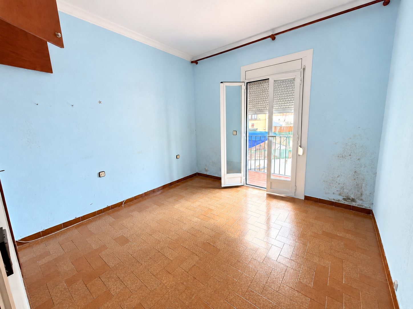 Dormitorio vacío con paredes desgastadas y balcón.png