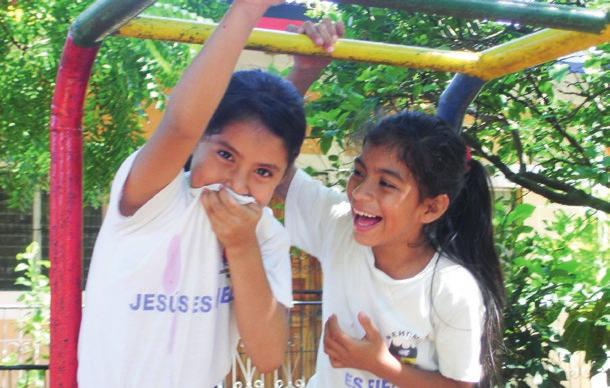 Zwei lachende Mädchen auf einem farbigen Klettergerüst – eines verdeckt den Mund mit dem T-Shirt. Jessica erinnert sich in ihrer Kolumne an einen Moment aus ihrem Kurzzeiteinsatz in Nicaragua, Südamerika.