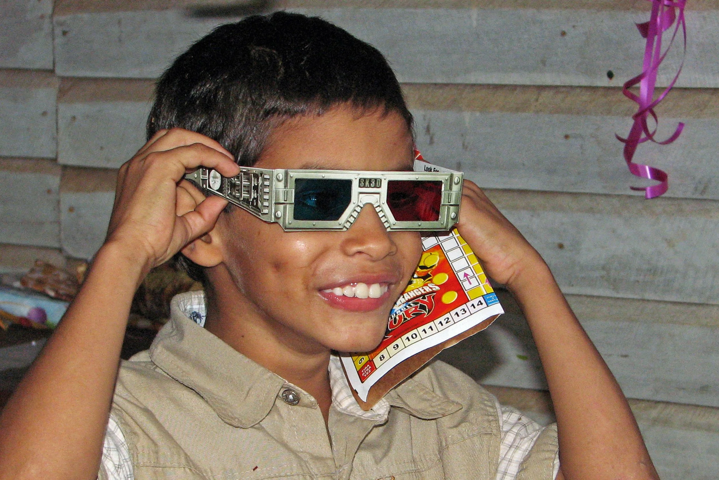 Grinsender Junge mit alter 3D-Brille – symbolisiert die lebendigen, tiefen Einblicke, die Videos und Filme von Latin Link in unsere Arbeit in Lateinamerika und die Einsatzmöglichkeiten geben.